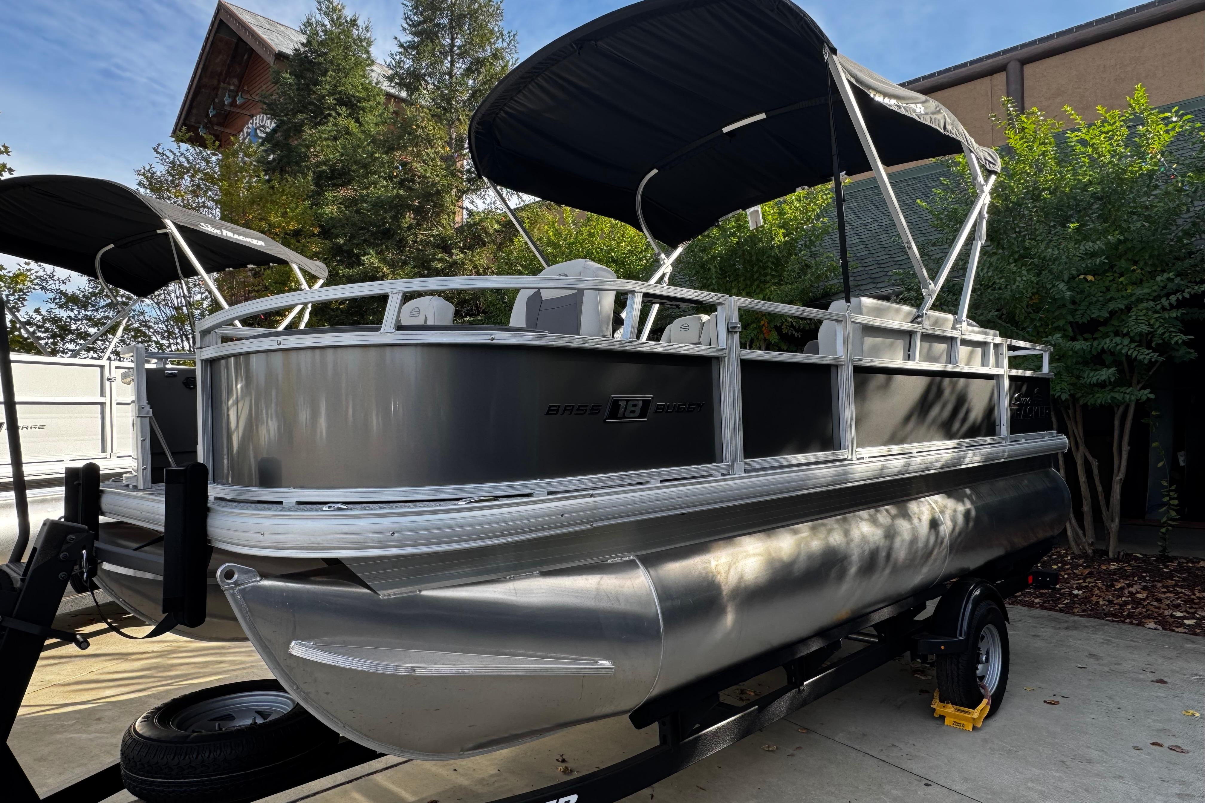 2026 Sun Tracker Bass Buggy 18 DLX pontoon boat with canopy, parked on trailer.