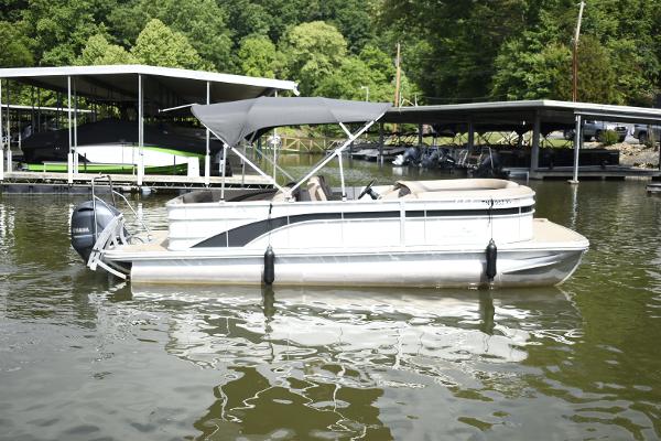 2023 Bennington 22 SXCW pontoon boat docked on a calm lake.