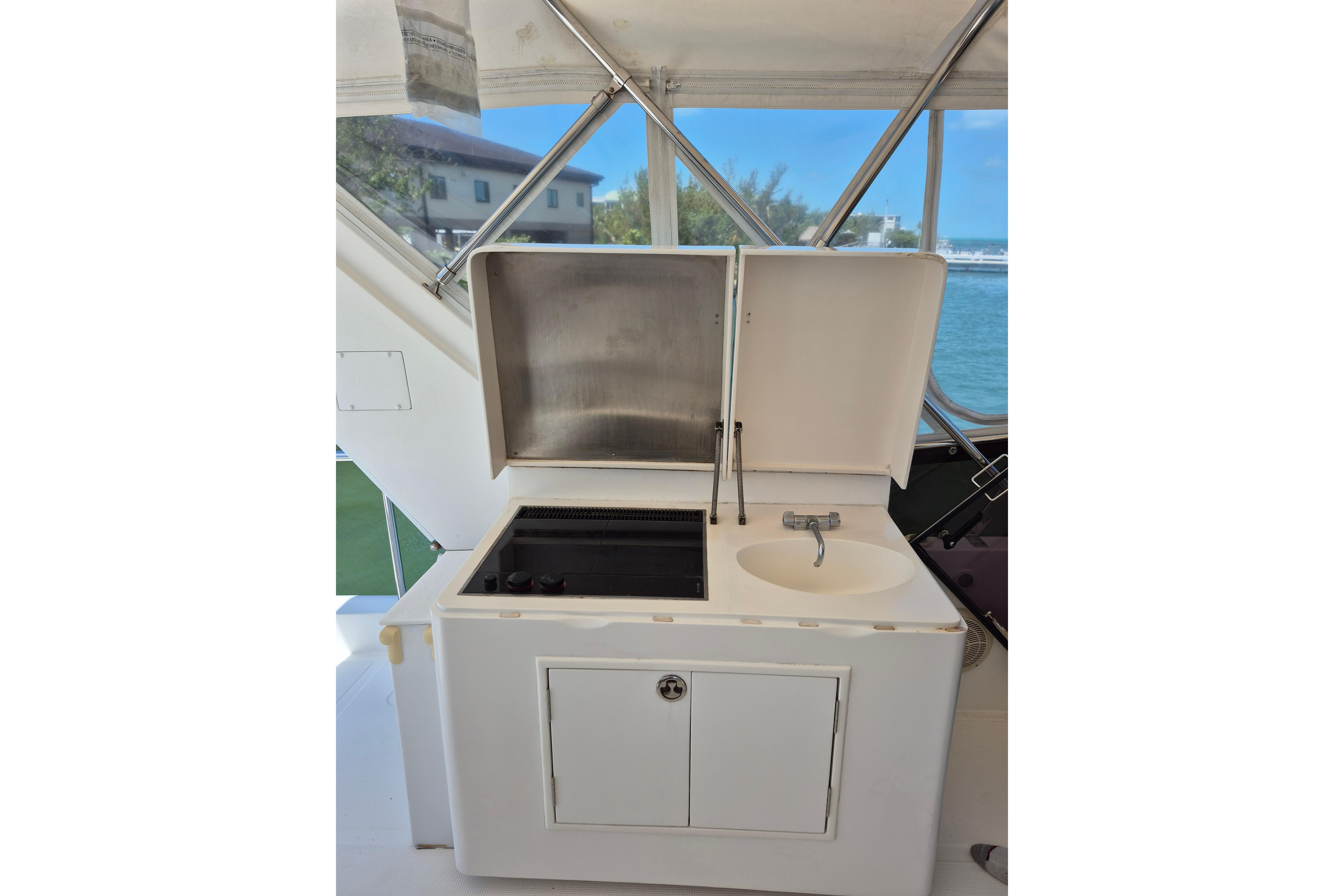 2006 Altima Flybridge yacht kitchenette with sink and stove, featuring outdoor views.