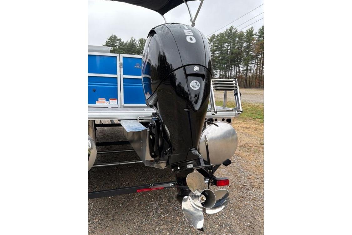2026 Sun Tracker Party Barge 22 DLX with powerful outboard motor, parked outdoors.