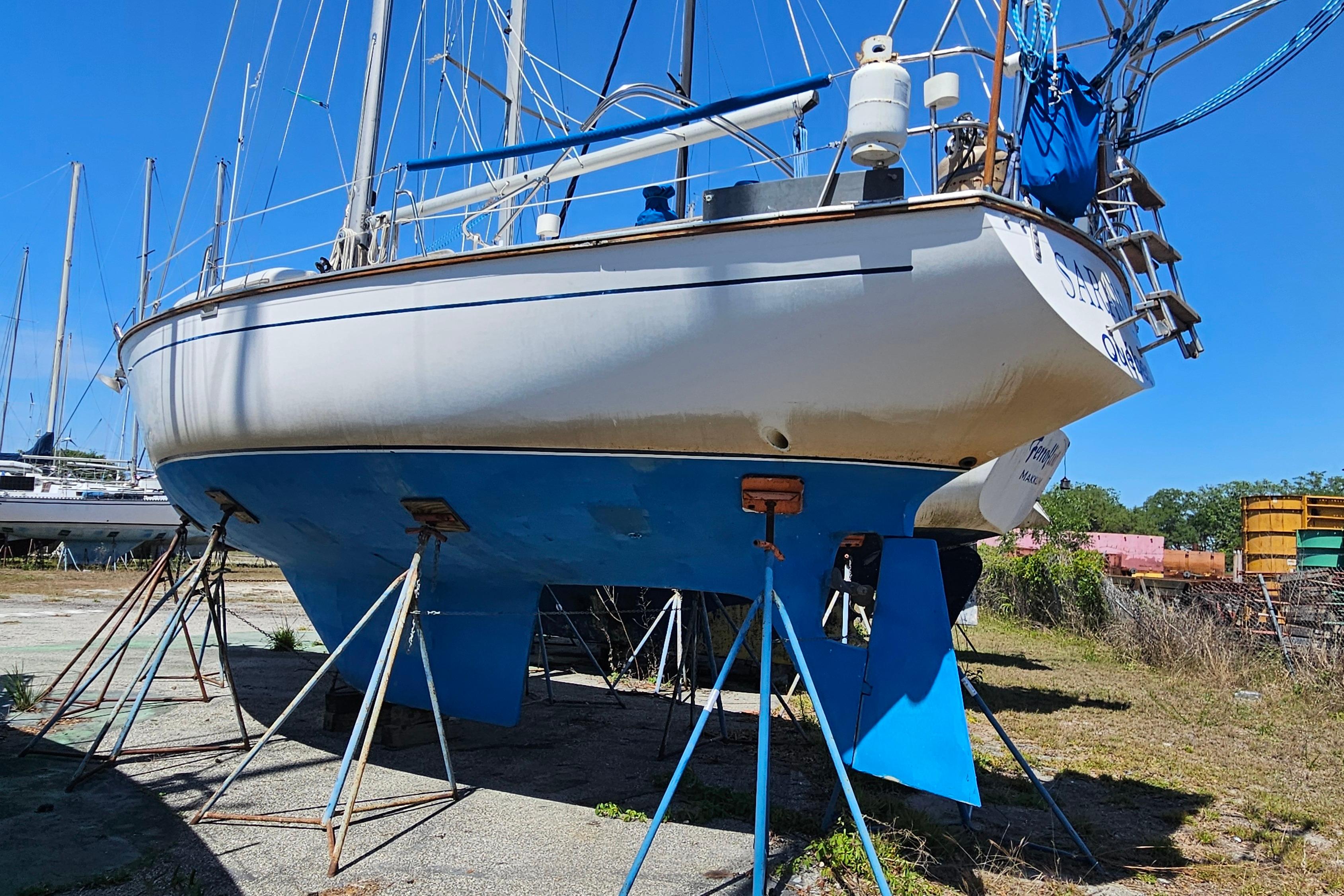 1979 Morgan 382 sailboat on stands, blue hull, in a boatyard under clear sky.