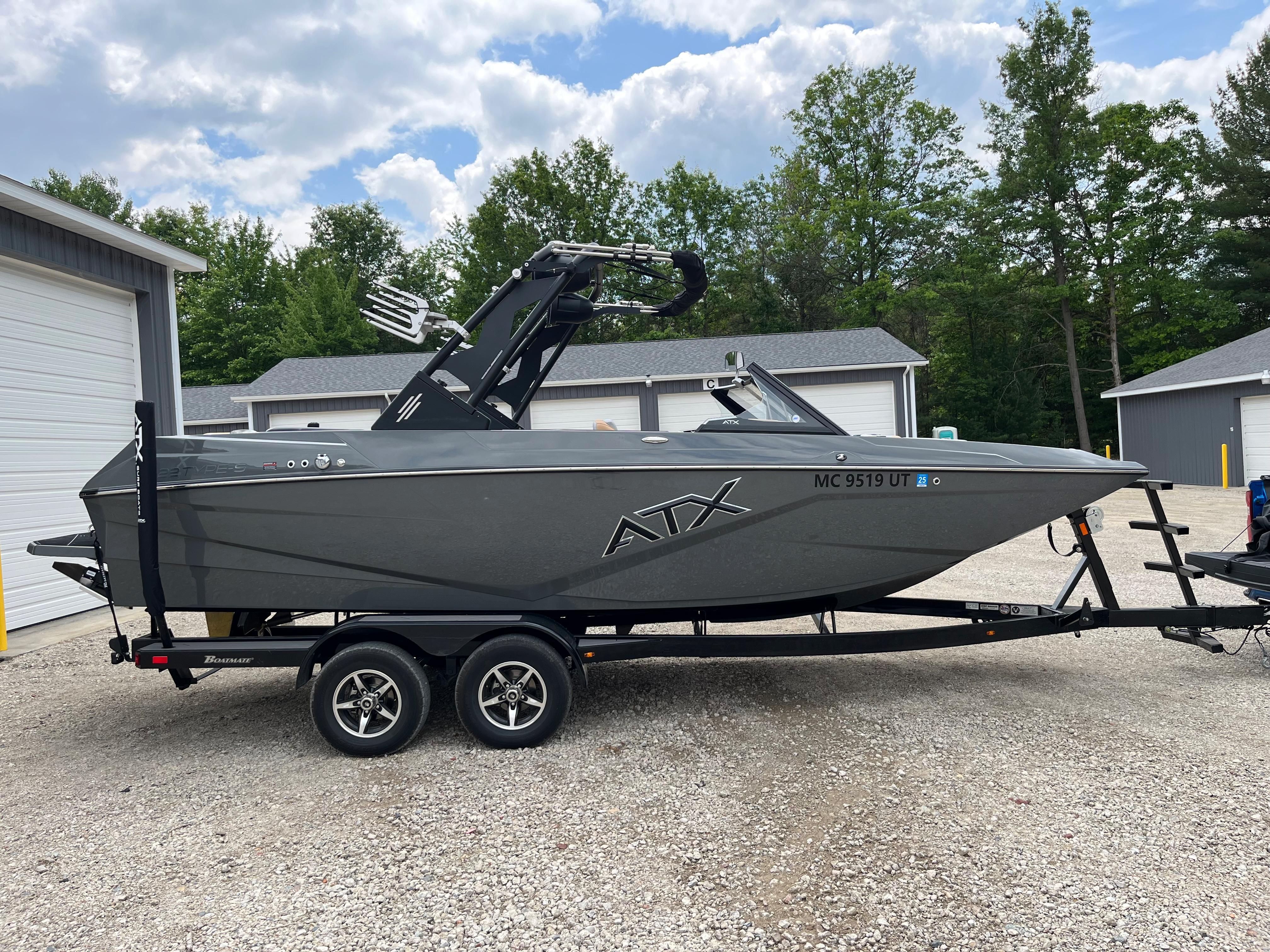 A gray 2022 ATX Surf Boat 22 Type-S on a trailer in a yard.