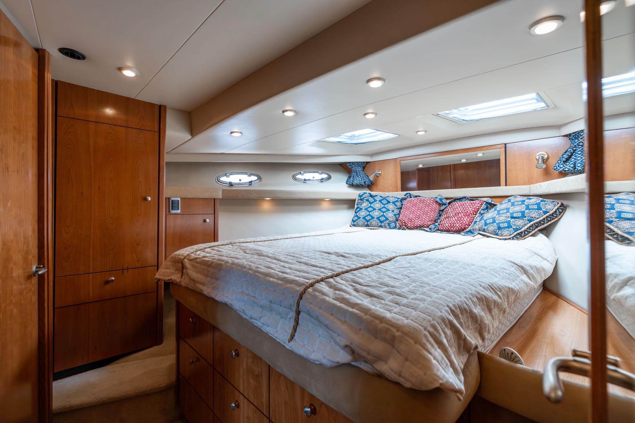 Luxurious bedroom interior of 2003 Meridian 490 Pilothouse yacht with cozy bedding and wood accents.