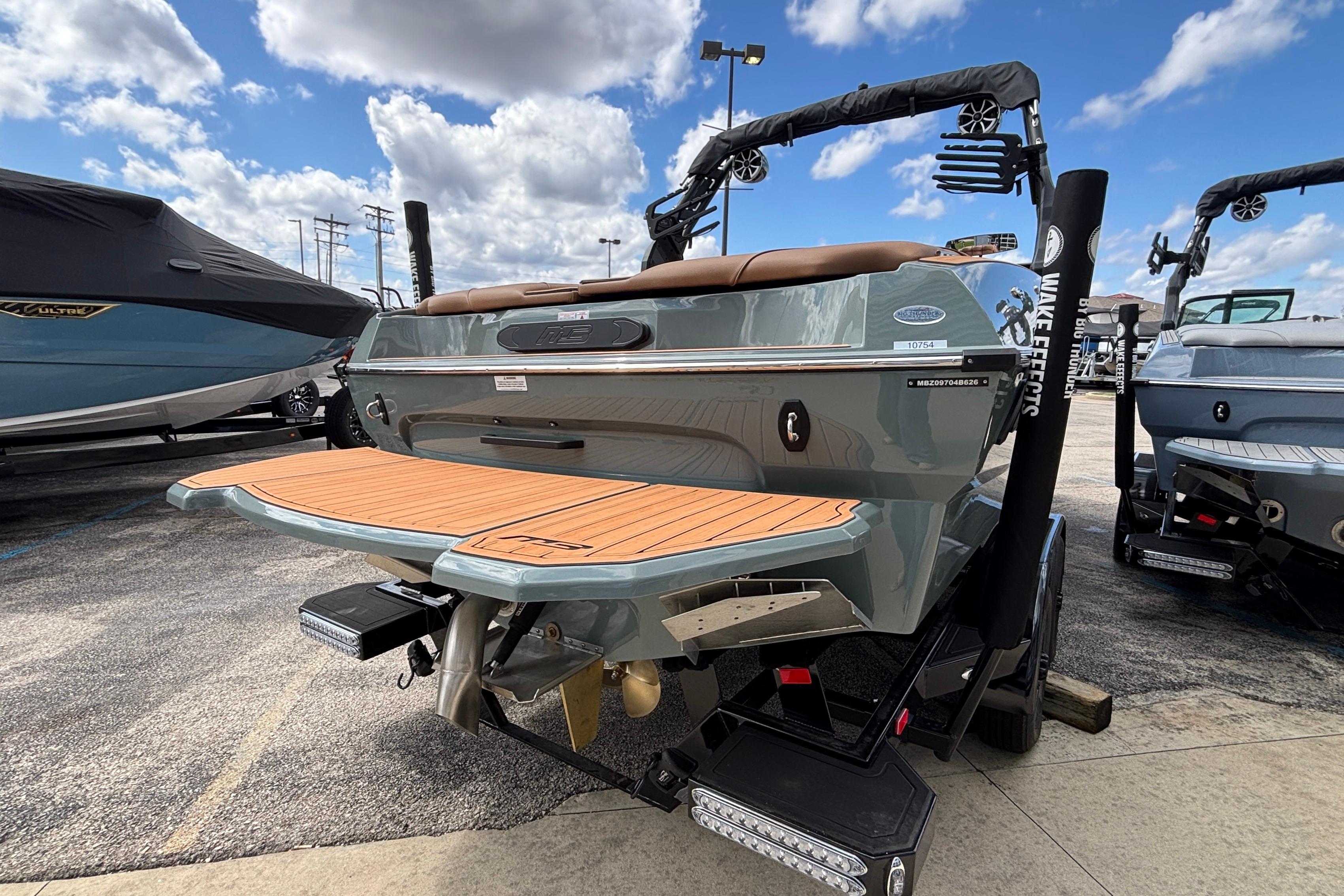 2026 MB B52 23 Classic boat with teak swim platform, parked outdoors under blue sky.