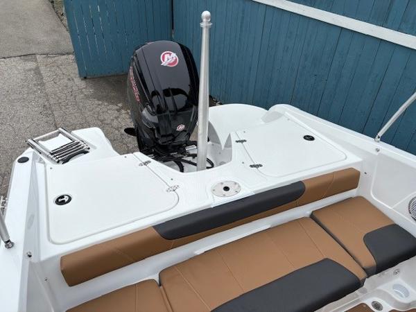 2025 Tahoe 185 S boat with outboard motor and tan seating, docked by blue fence.