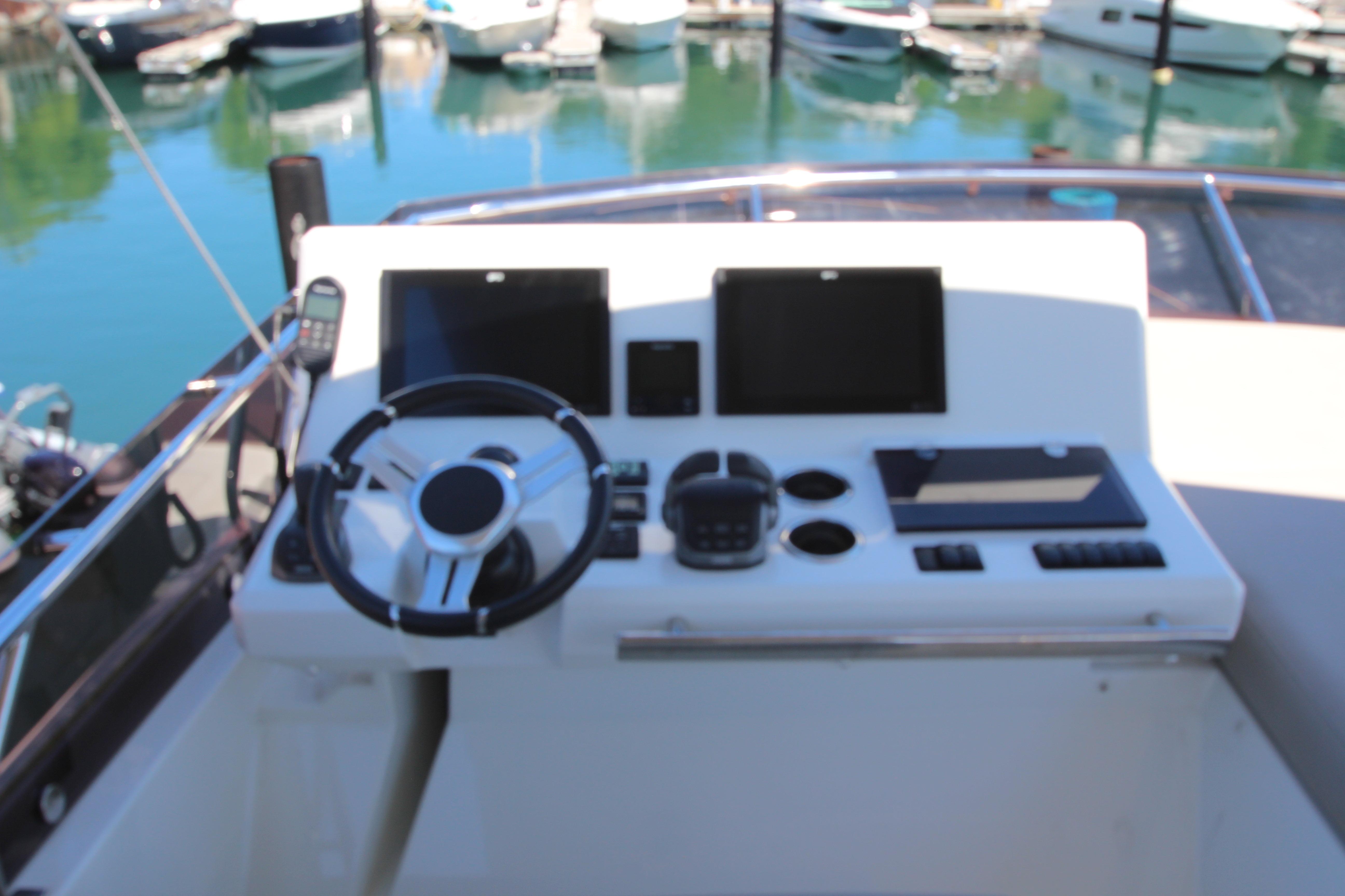 Control panel of a 2022 Prestige 520 yacht with steering wheel and navigation screens.