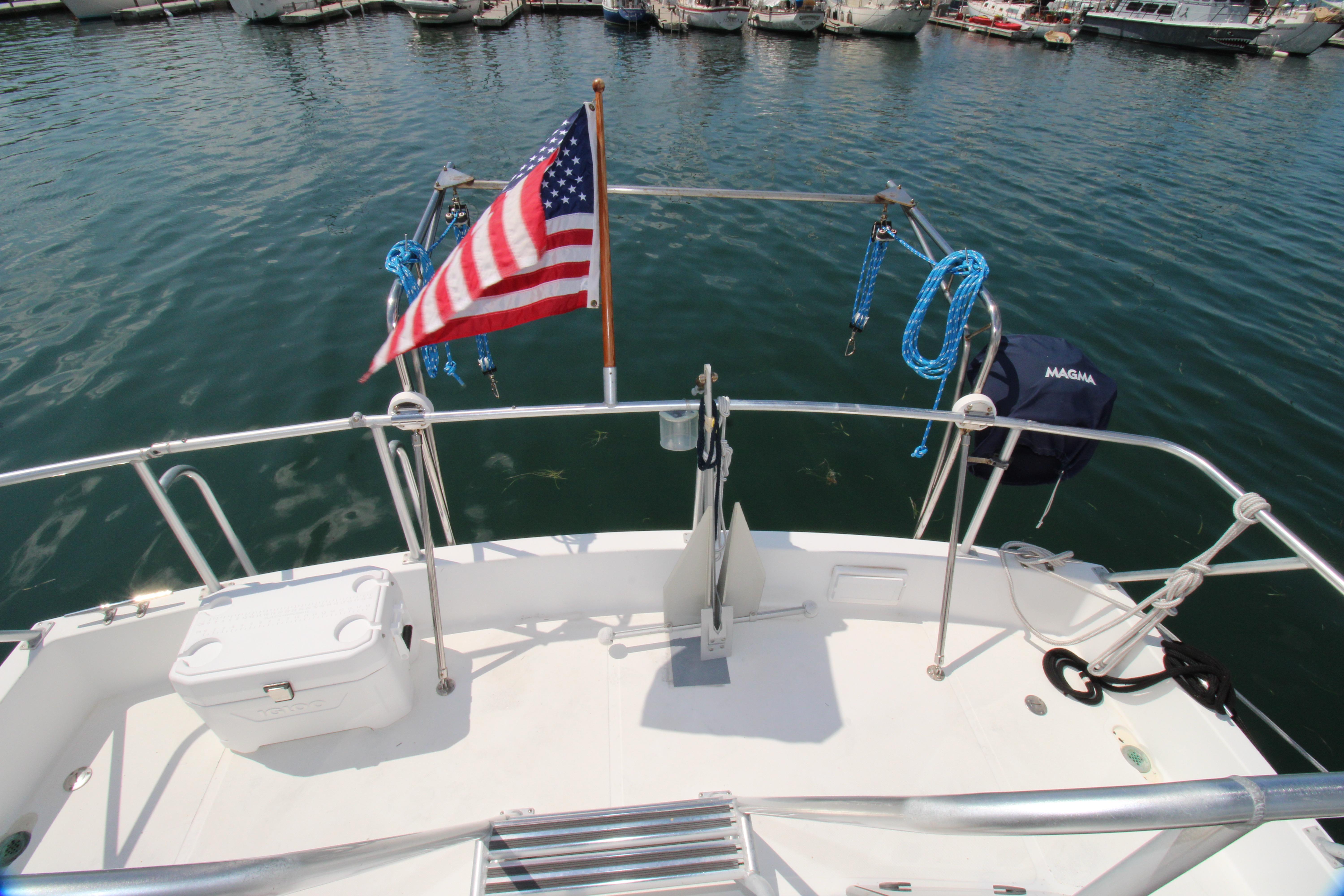 Deck view of 2000 Ricker 42 Classic boat with American flag and marina backdrop.