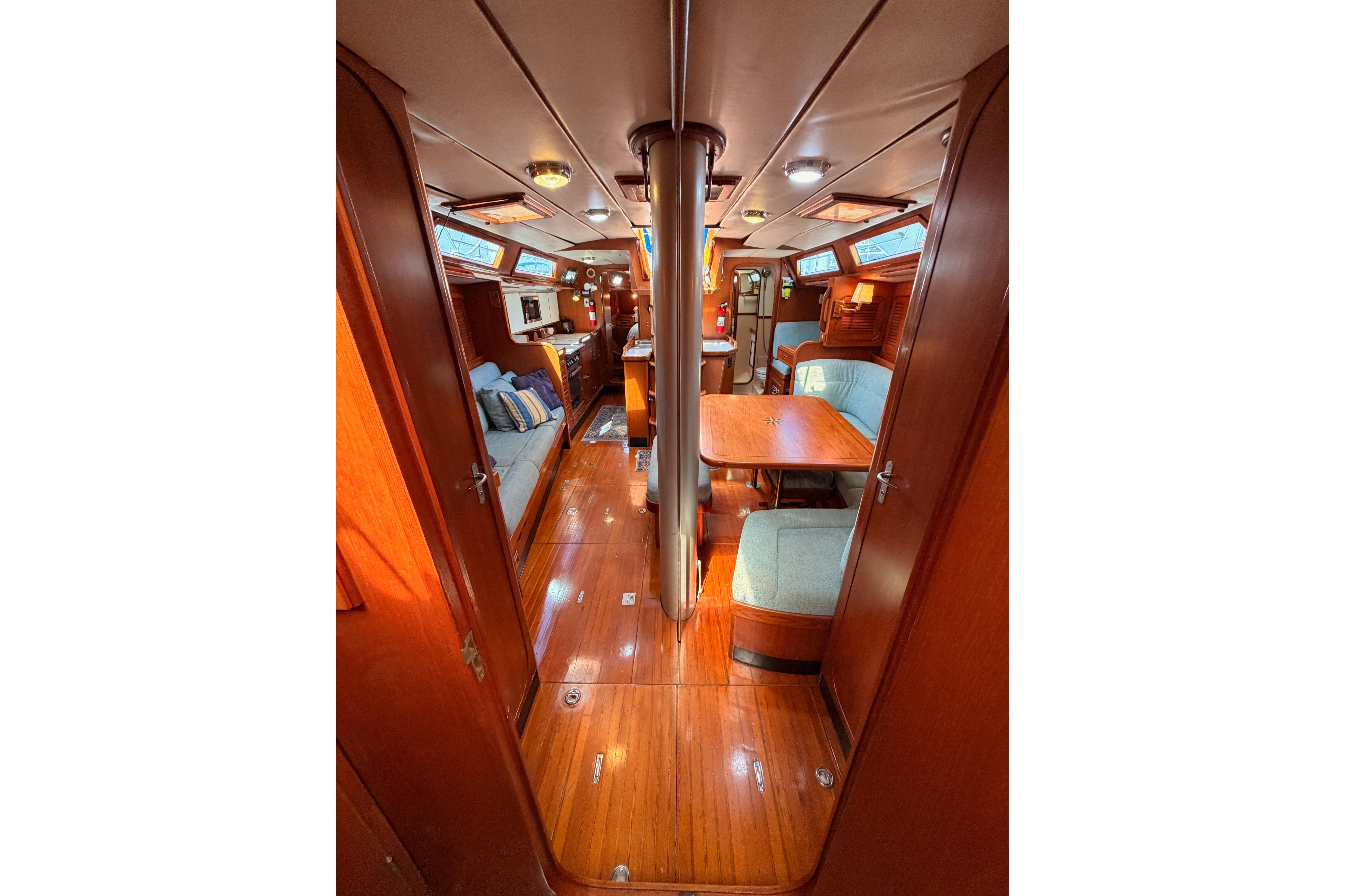 Interior of 1991 Hylas 51 yacht, featuring polished wood and cozy seating area.