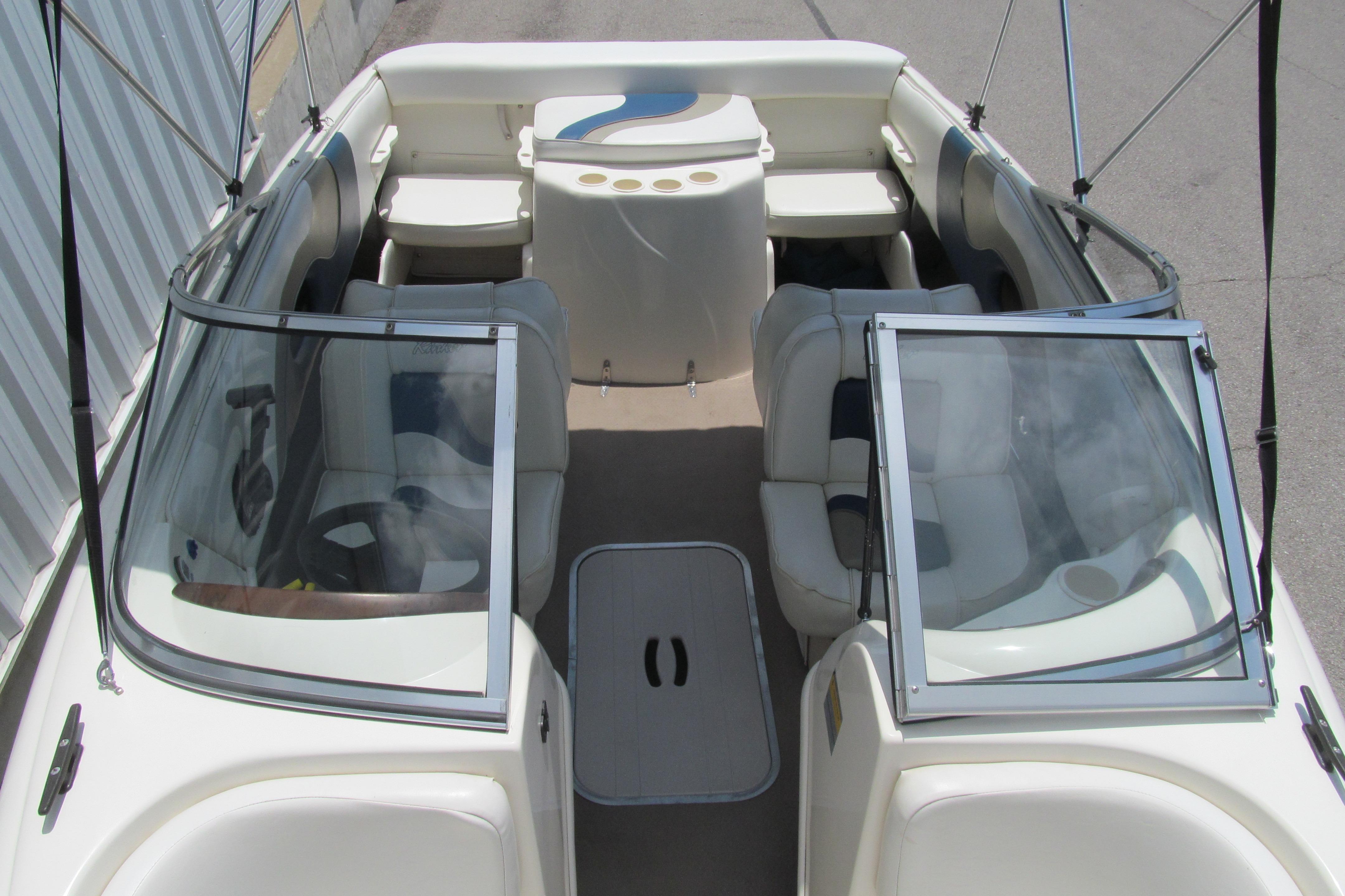 2000 Rinker boat interior with seating, windshield, and steering wheel, docked near a metal structure.