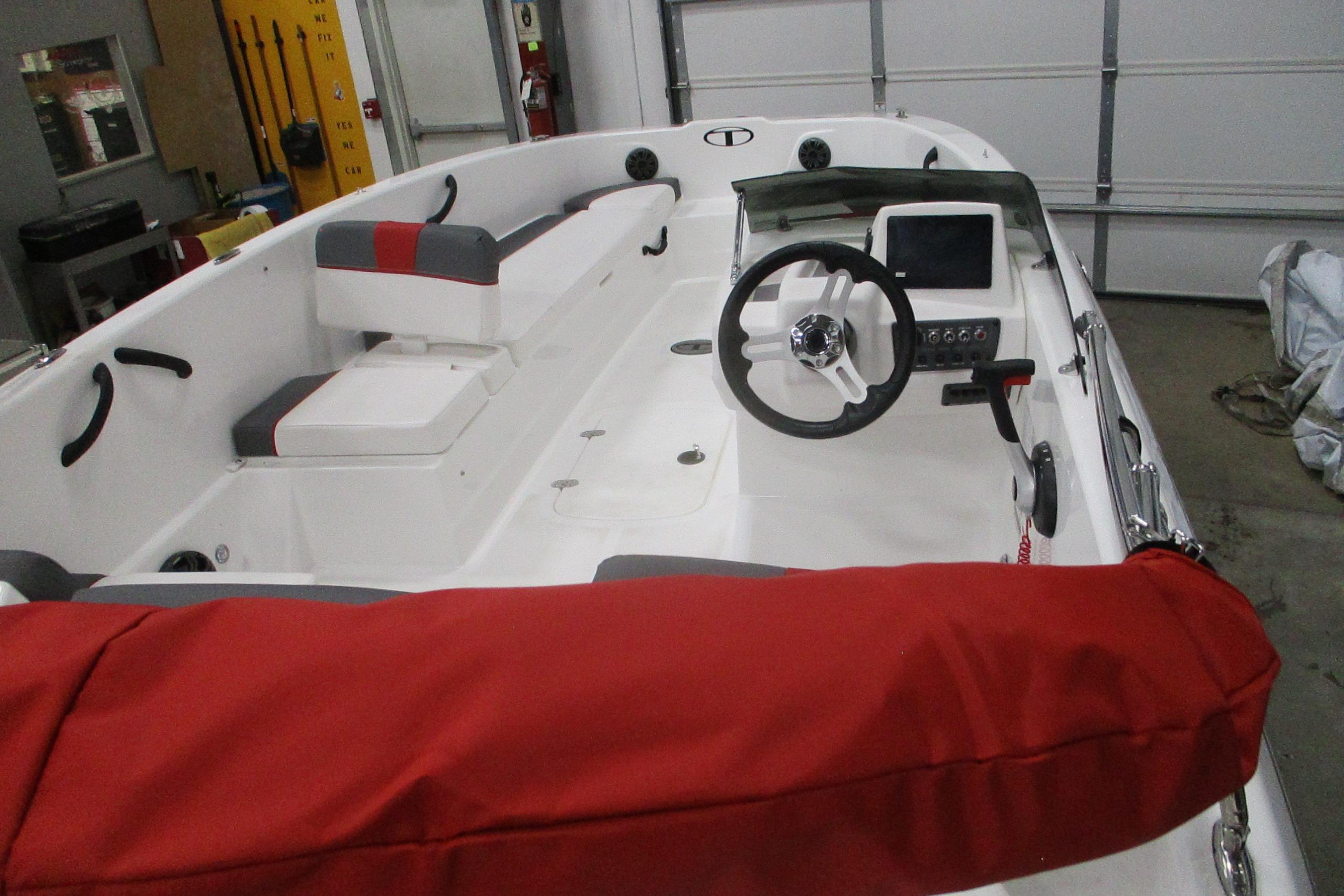 2025 Tahoe T18 boat interior with steering wheel, red seating, and control panel.