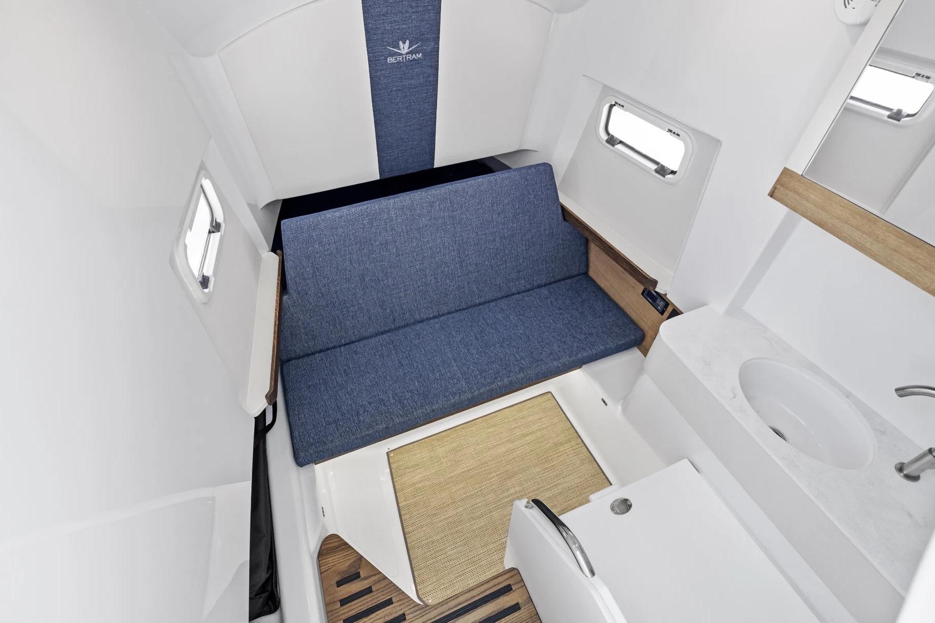 Manufacturer Provided Image: Interior of 2026 Bertram 34 CC boat with blue seating, windows, and compact sink area.
