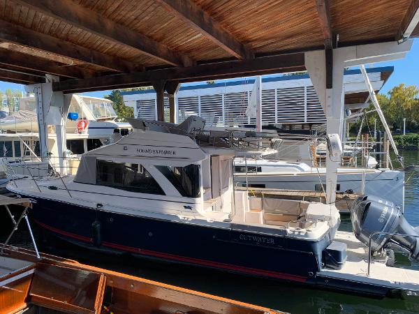 2021 Cutwater C-32 CB boat docked under a wooden shelter.