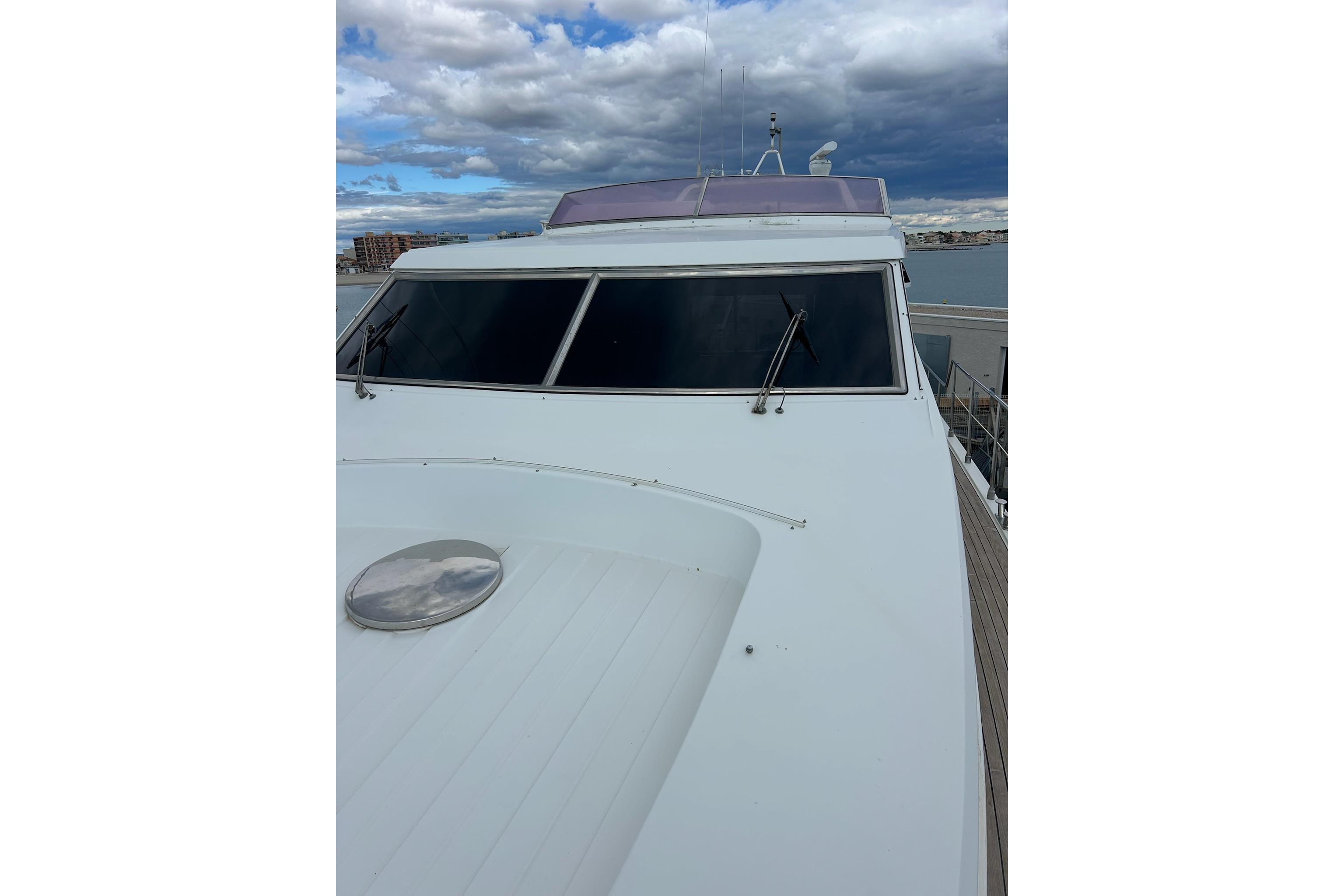 San Lorenzo 57 yacht, 1990 model, featuring sleek white deck and tinted windows under cloudy skies.