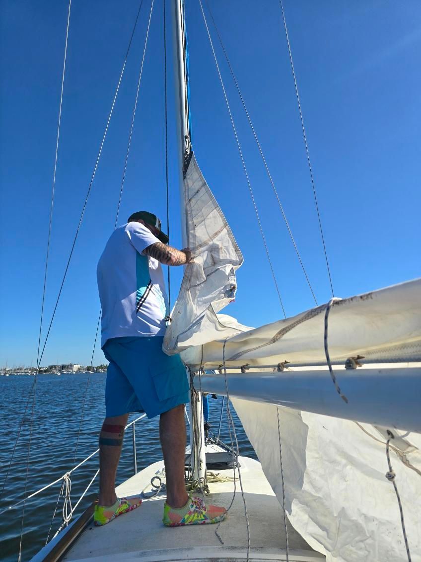 A man adjusts the sail on a Hunter 25.5 sailboat.