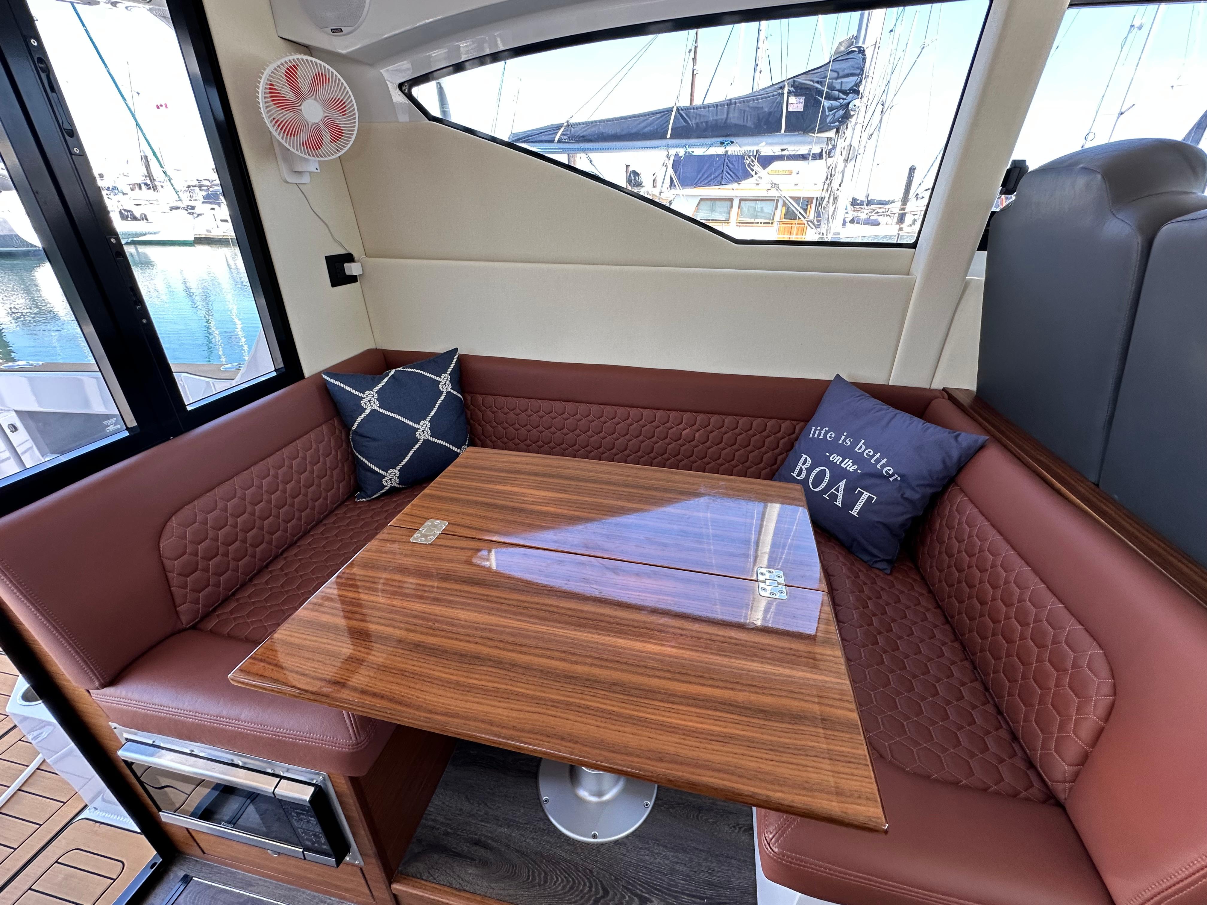 2024 Herley 11 Explorer interior with brown seating, wooden table, and nautical-themed pillows.