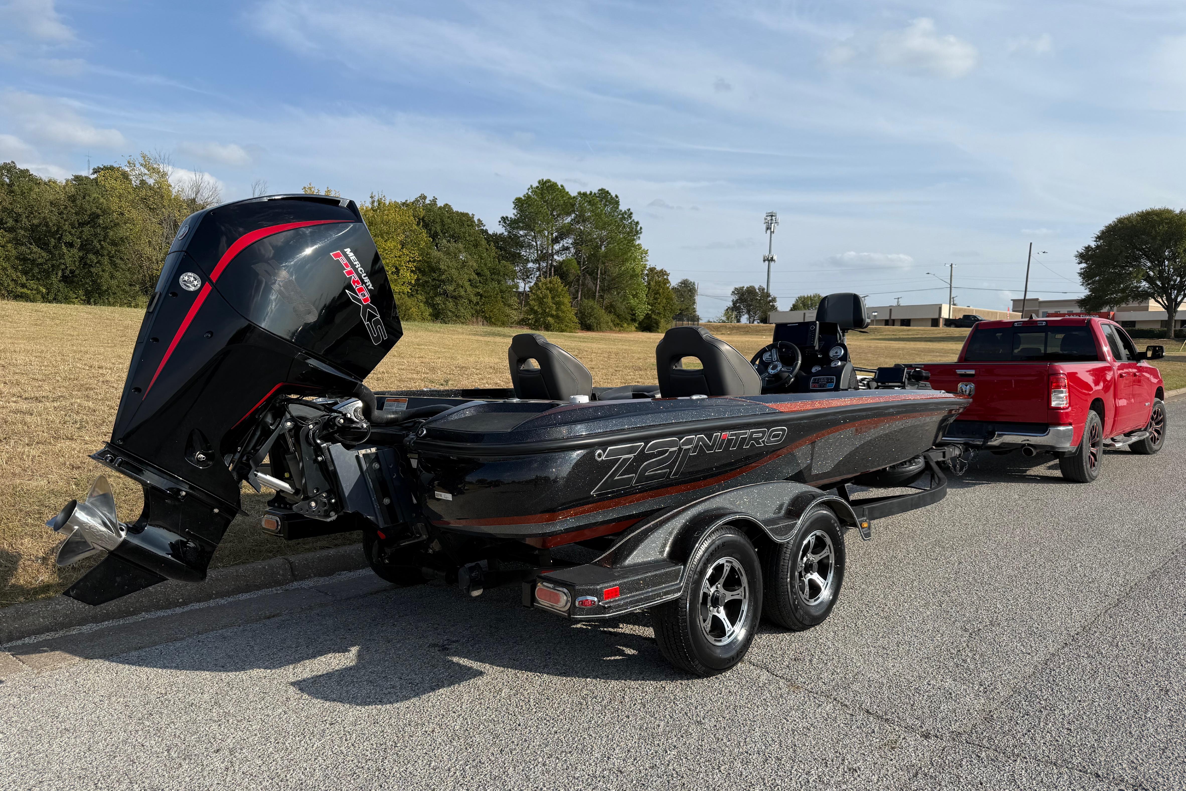 2019 Nitro Z21 Pro boat on trailer, hitched to red truck, parked roadside.