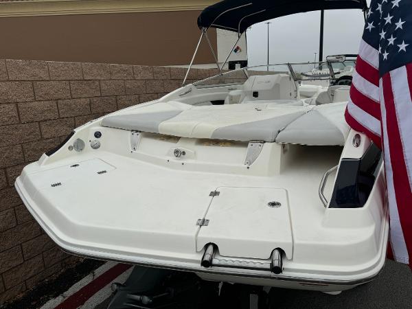 2006 Larson LXi 248 boat with American flag, rear view, parked near brick wall.