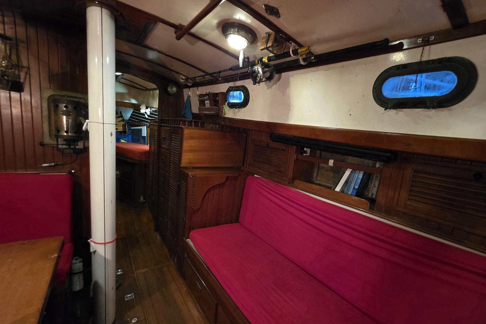 Interior of 1982 Tayana 37 sailboat with wooden paneling and red seating.