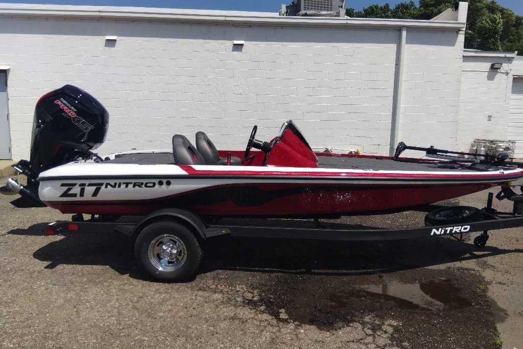 2026 Nitro Z17 boat with trailer, parked outdoors, featuring sleek red and white design.