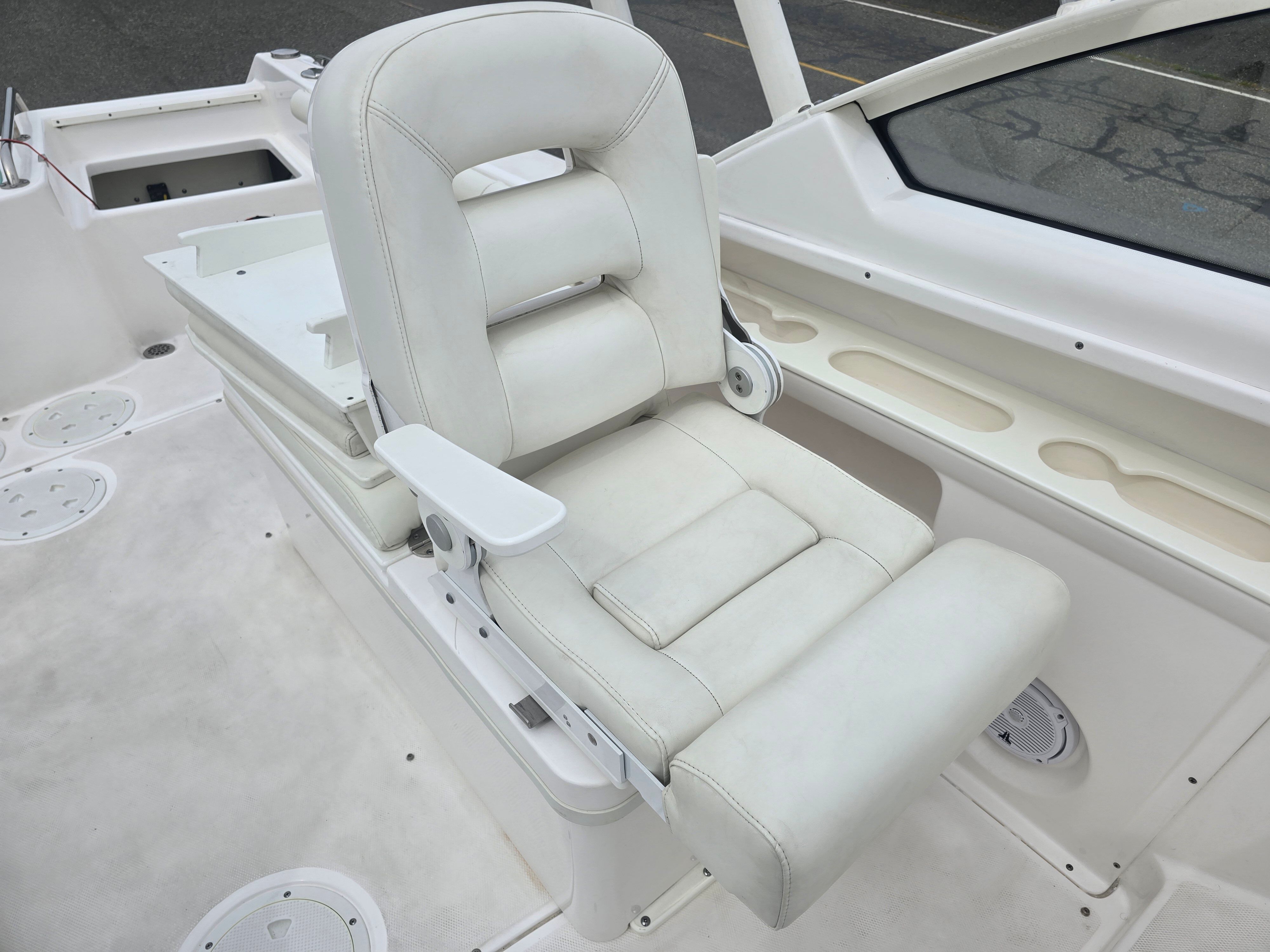 White captain's chair on a boat with armrests and cushioning.