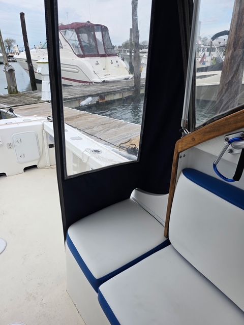 Interior view of a boat with white and blue seats, docked at a marina.