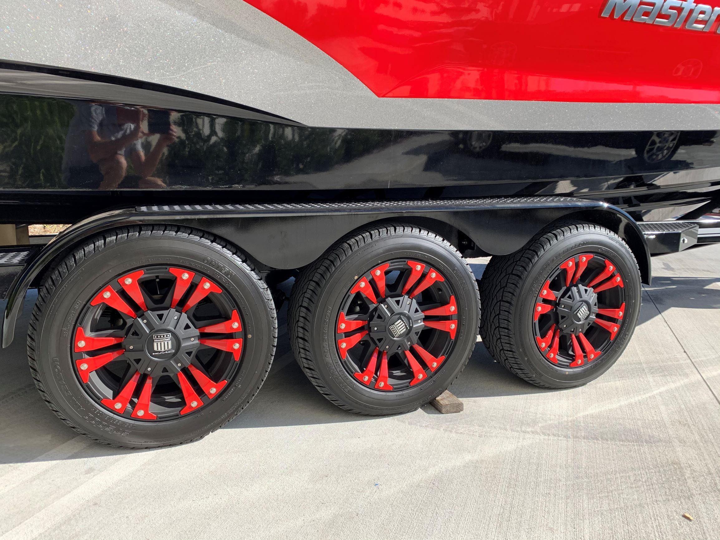 A 2020 MasterCraft X24 boat on a trailer with striking red and black wheels.