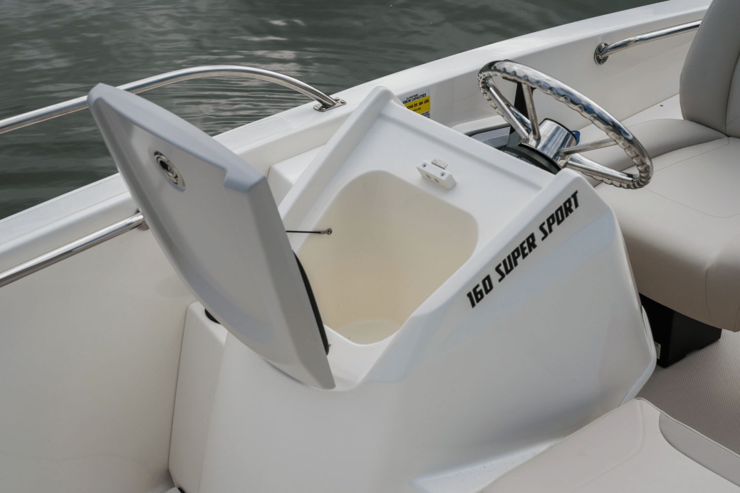 The image shows the cockpit of a Boston Whaler 160 Super Sport with an open storage compartment.