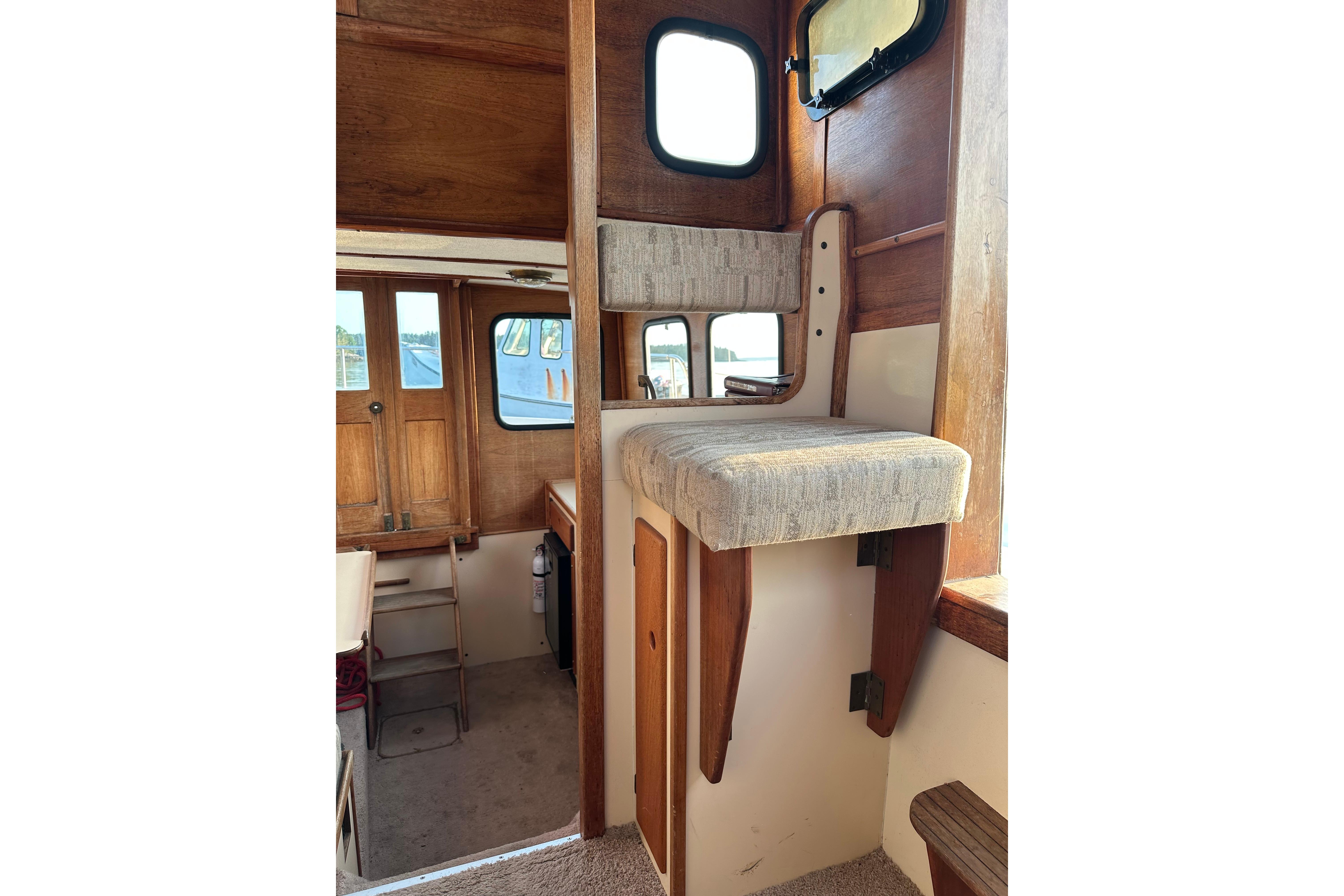 Interior of a 1985 Nordic Tug 26, featuring wooden accents and a cushioned seat.