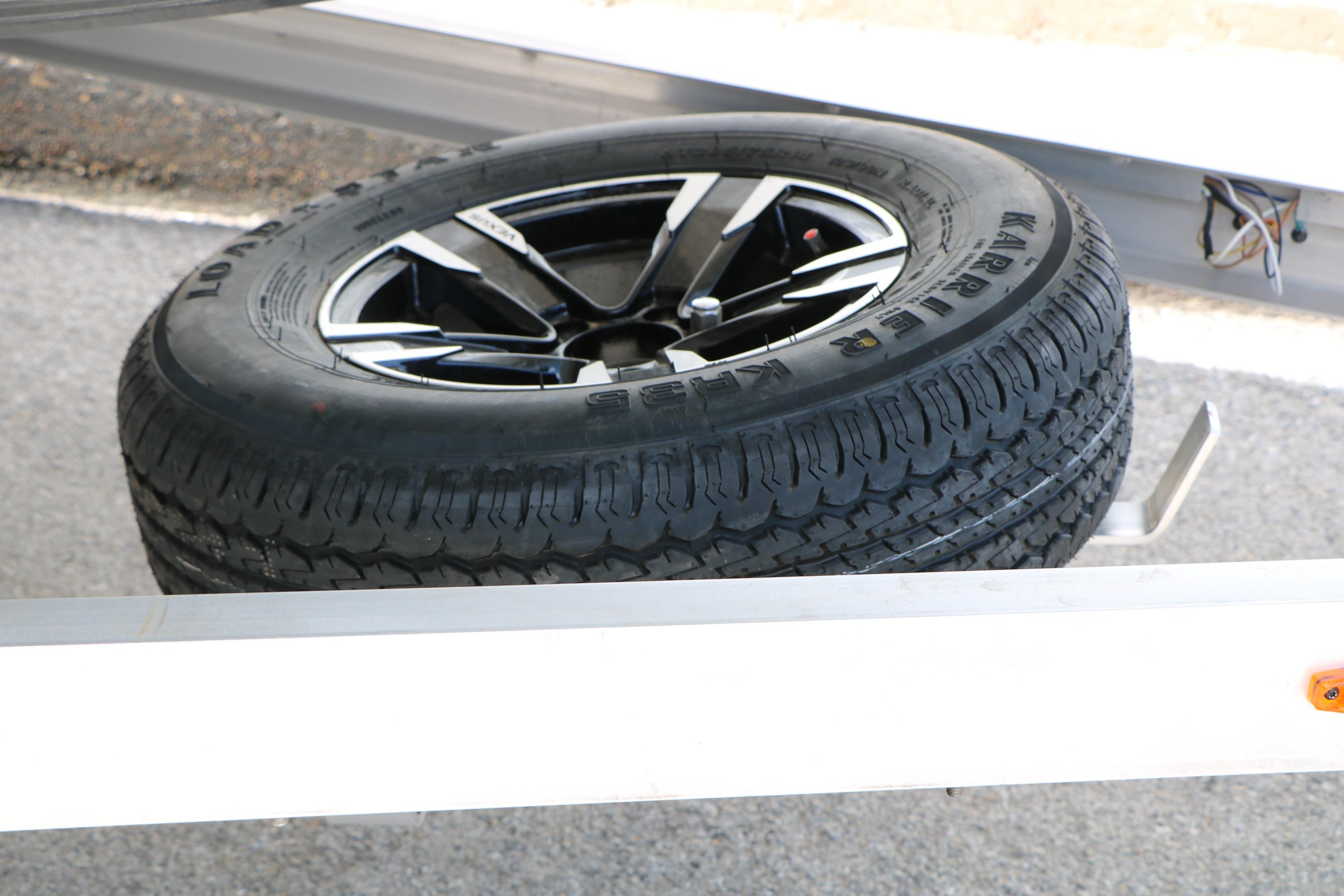 Spare tire on a Vexus Defender 201 trailer, 2026 model, resting on pavement.