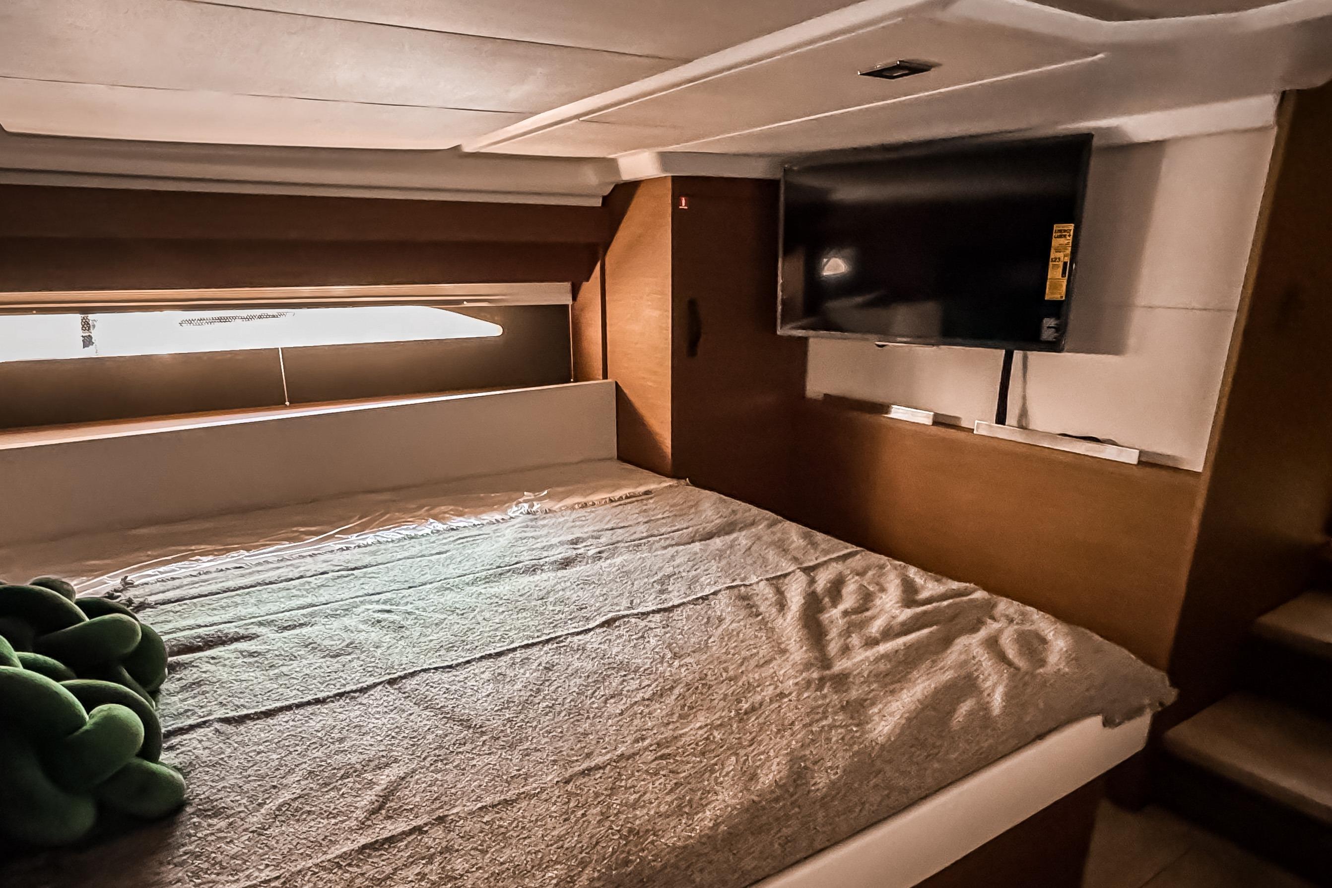 Interior of 2026 Wellcraft 44 Explorer with bed and TV.