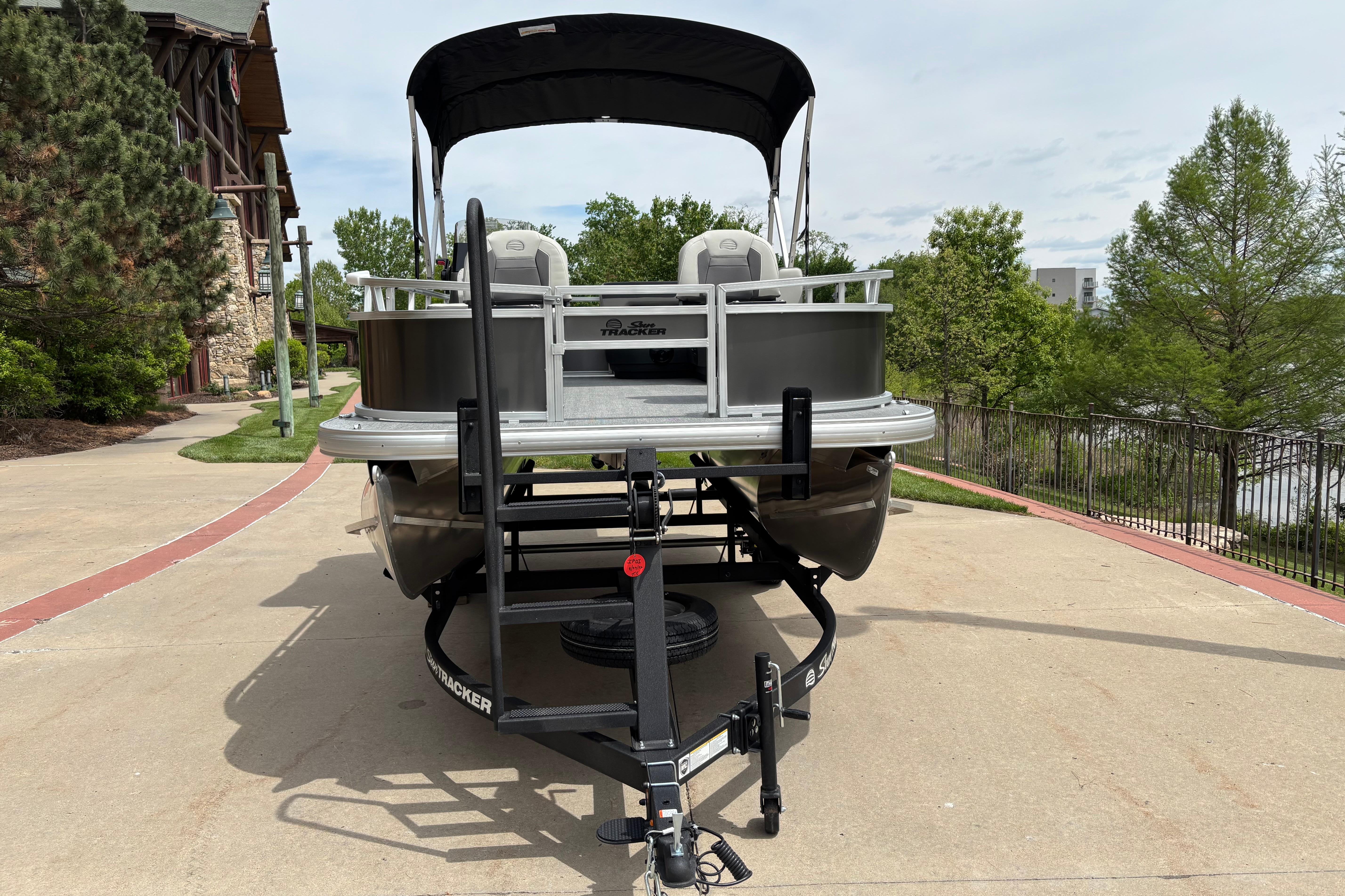 2026 Sun Tracker Bass Buggy 16 XL Select pontoon boat on trailer, parked outdoors.