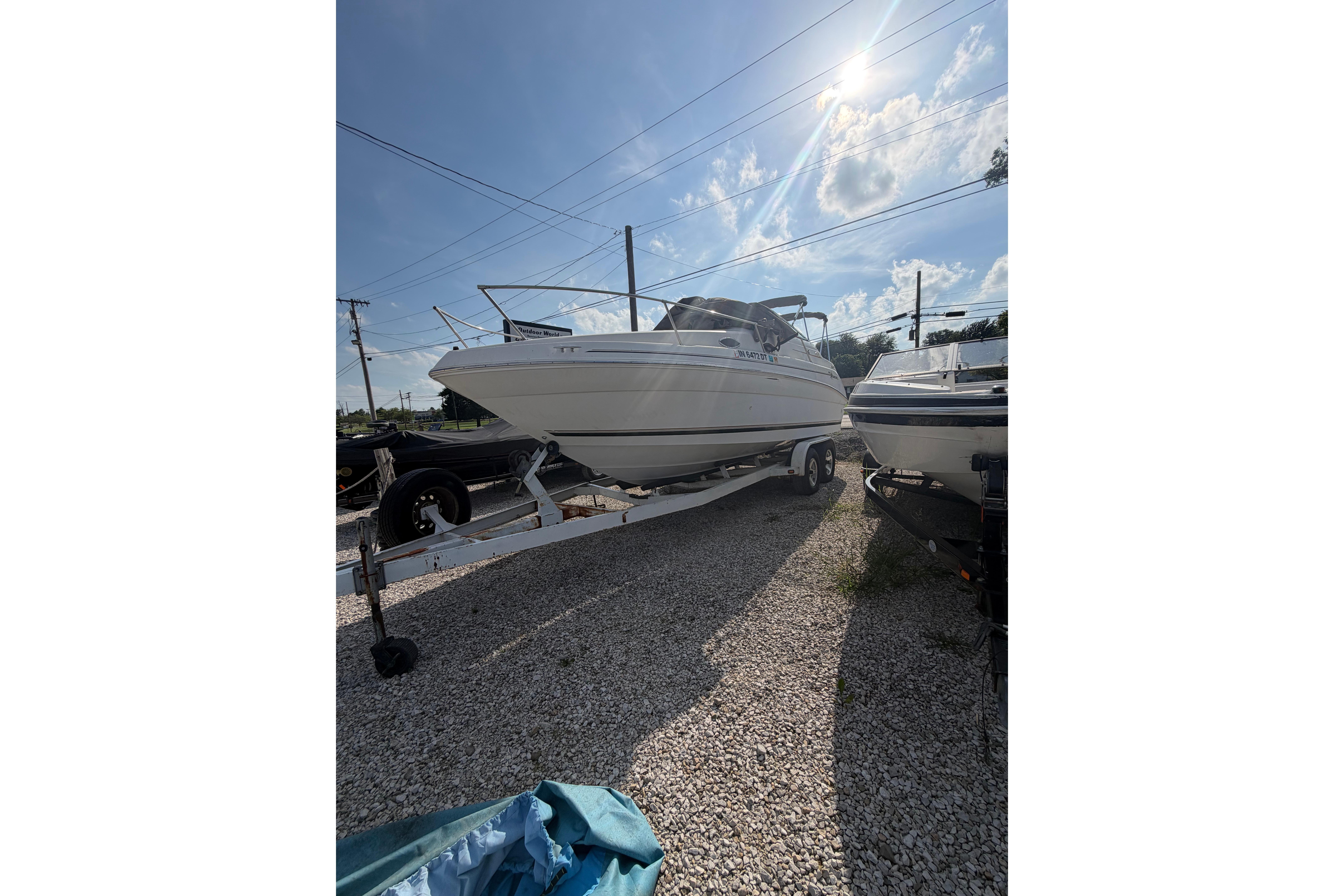 1999 Sea Ray 240 Sundancer boat on trailer under sunny sky.