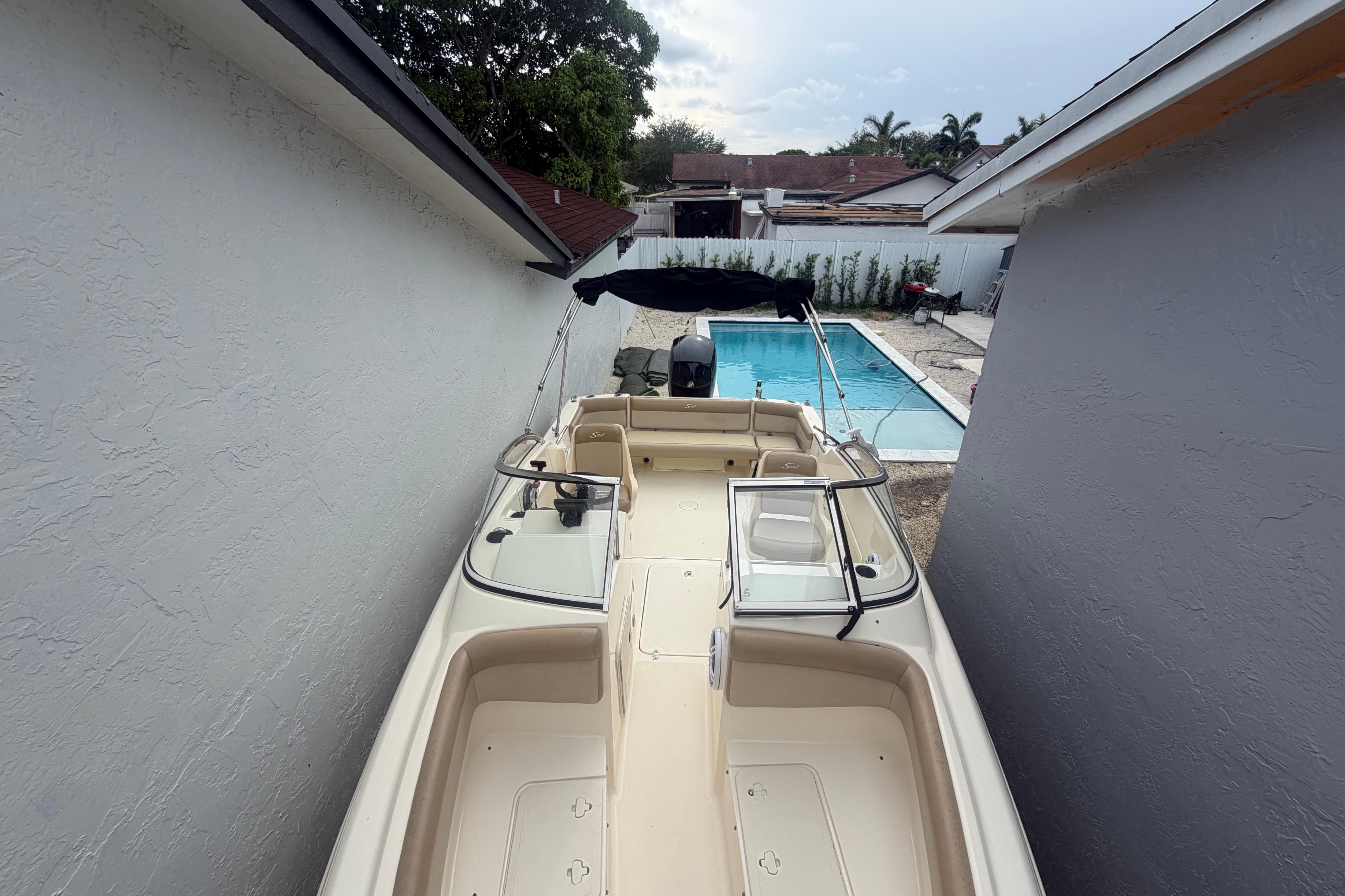 2023 Scout 210 Dorado boat parked beside a pool in a residential backyard.