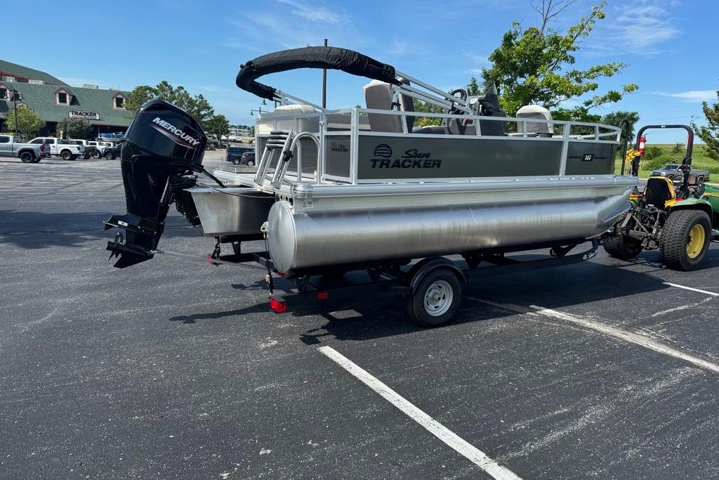 2026 Sun Tracker Bass Buggy 16 XL Select pontoon boat on trailer in parking lot.