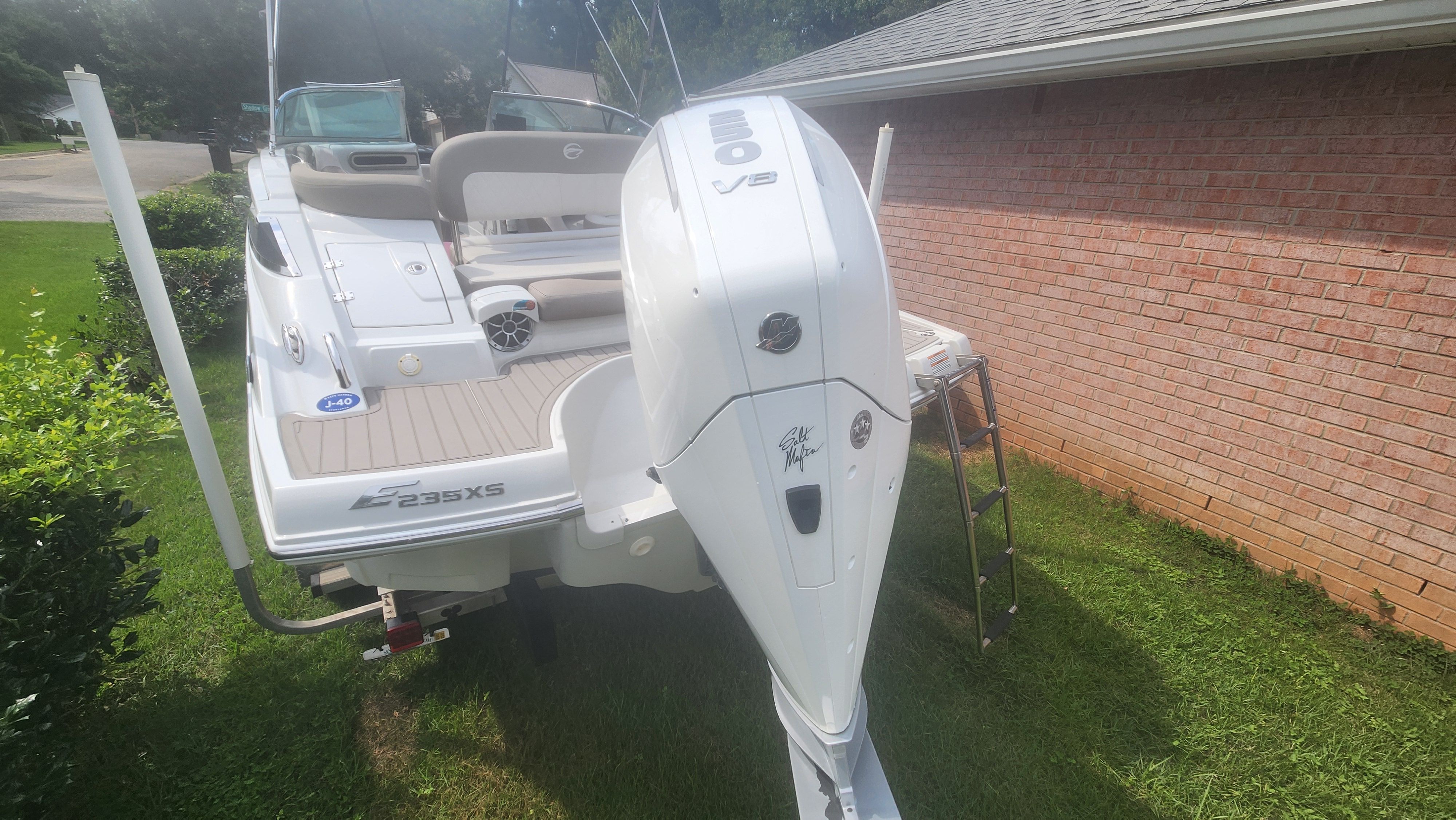 A 2019 Crownline Eclipse E235 XS boat is on a lawn next to a brick building.