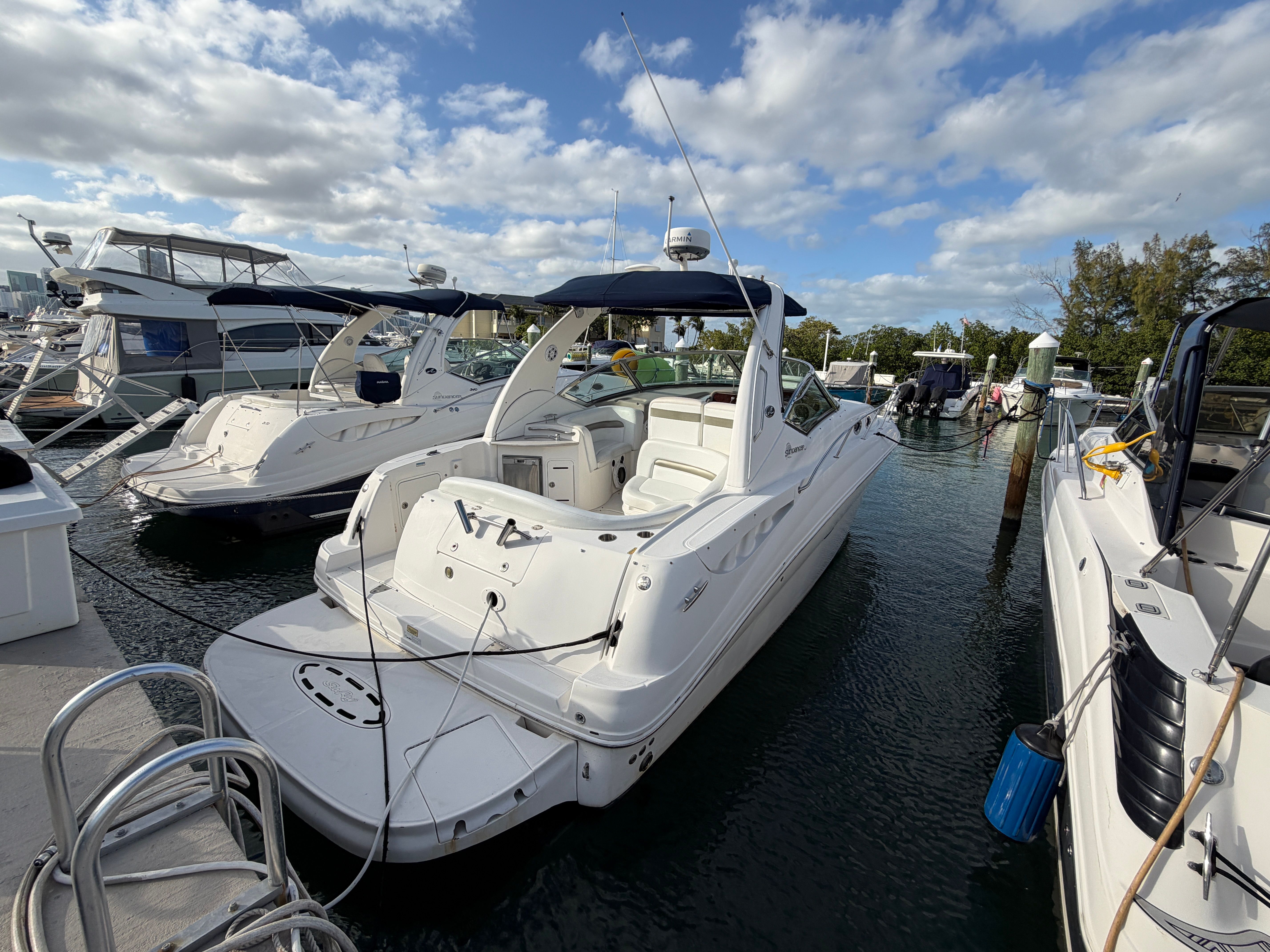 A 2006 Sea Ray Sundancer 320 docked at a marina. It features a sleek, white design.