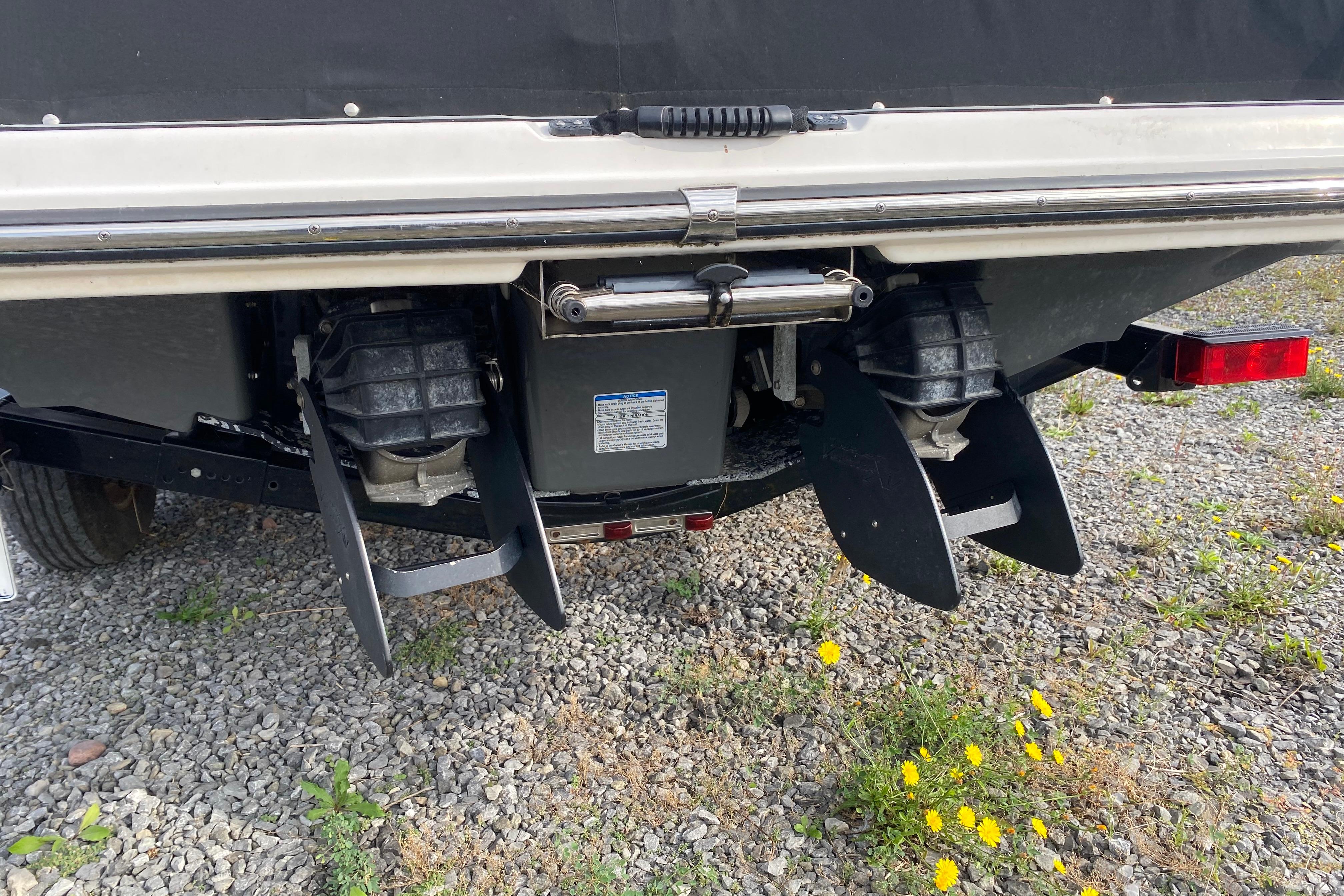 Rear view of 2015 Yamaha Boats 212X with dual jet drives on gravel.