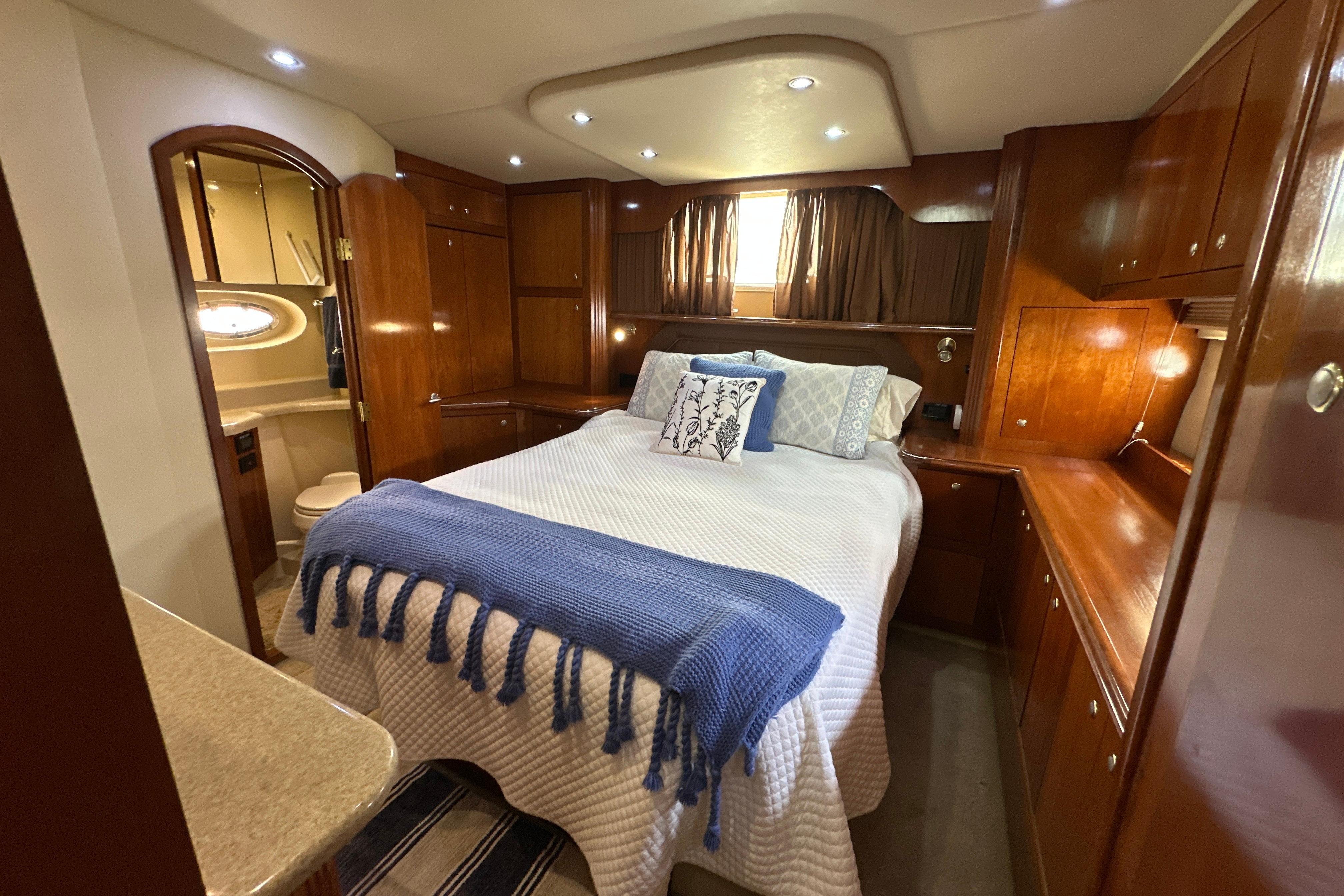 Luxurious 2004 Cruisers Yachts 405 Express Motoryacht bedroom with elegant wood finishes.