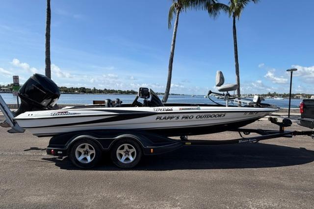 2005 Triton Tr-21X PD boat on trailer by waterfront, under palm trees.