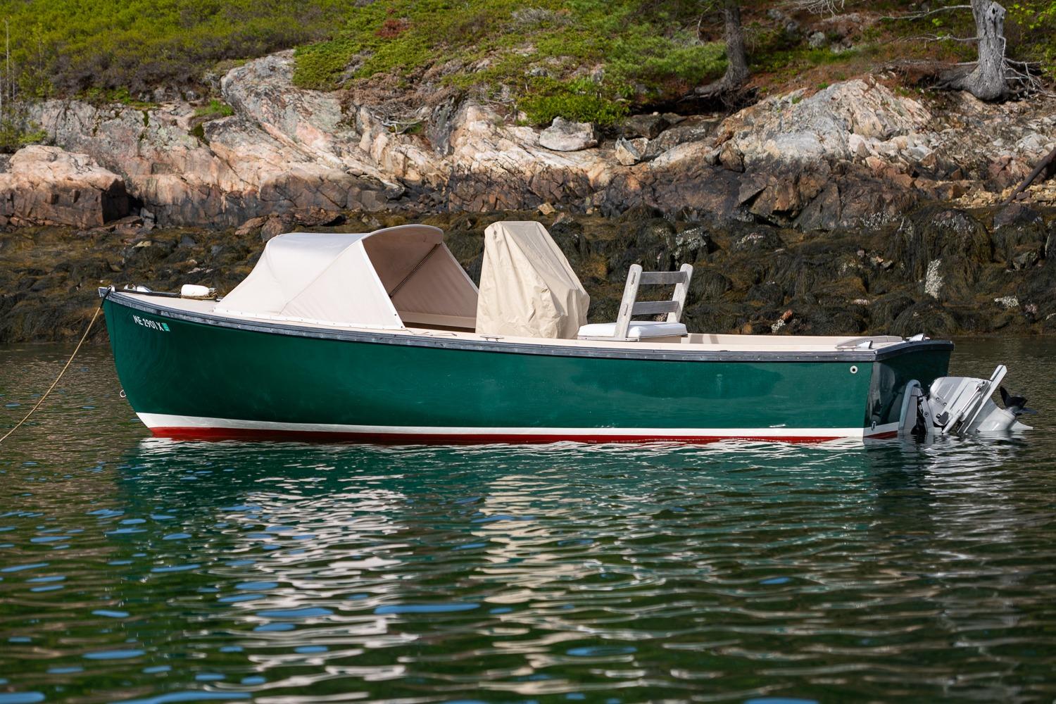 1989 Ellis 24 Open boat with green hull, anchored near rocky shoreline.