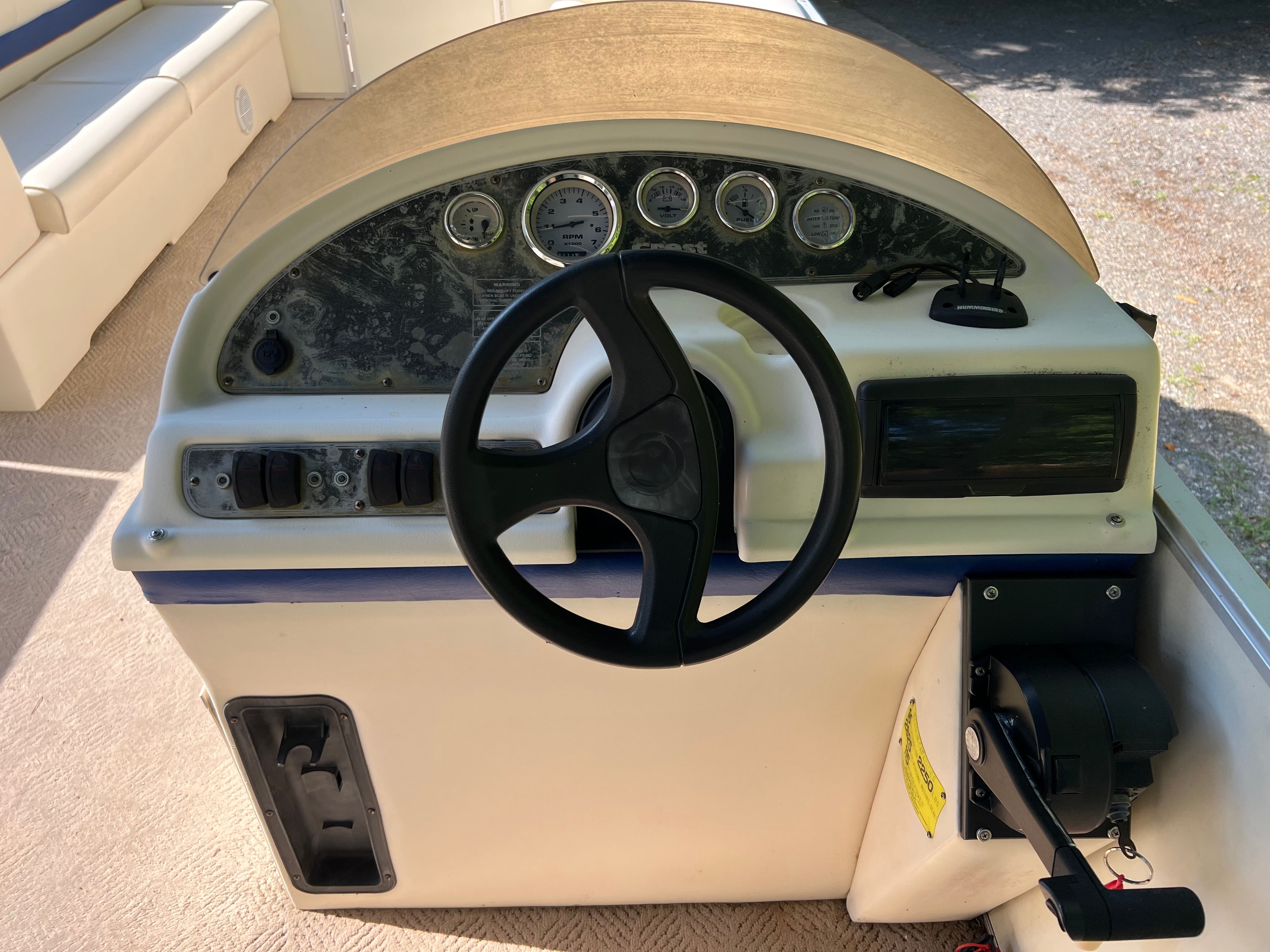 The image shows a boat's helm with multiple gauges and a steering wheel.