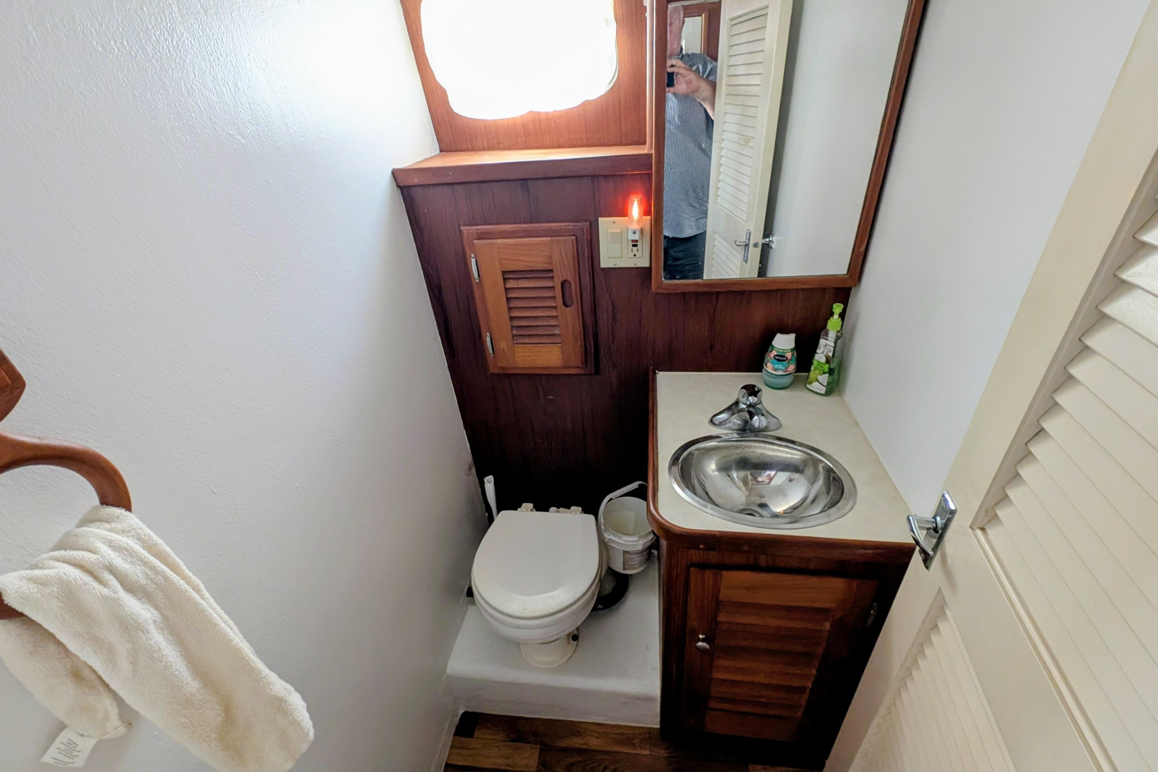 Compact bathroom in a 1998 Markley 46 boat, featuring a sink, toilet, and wooden cabinetry.