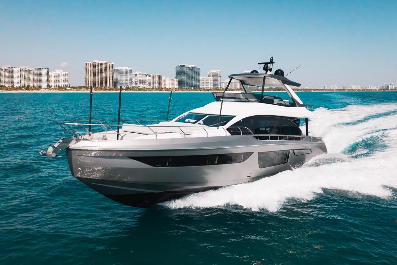 2023 Azimut Fly 68 yacht cruising on blue ocean near city skyline.