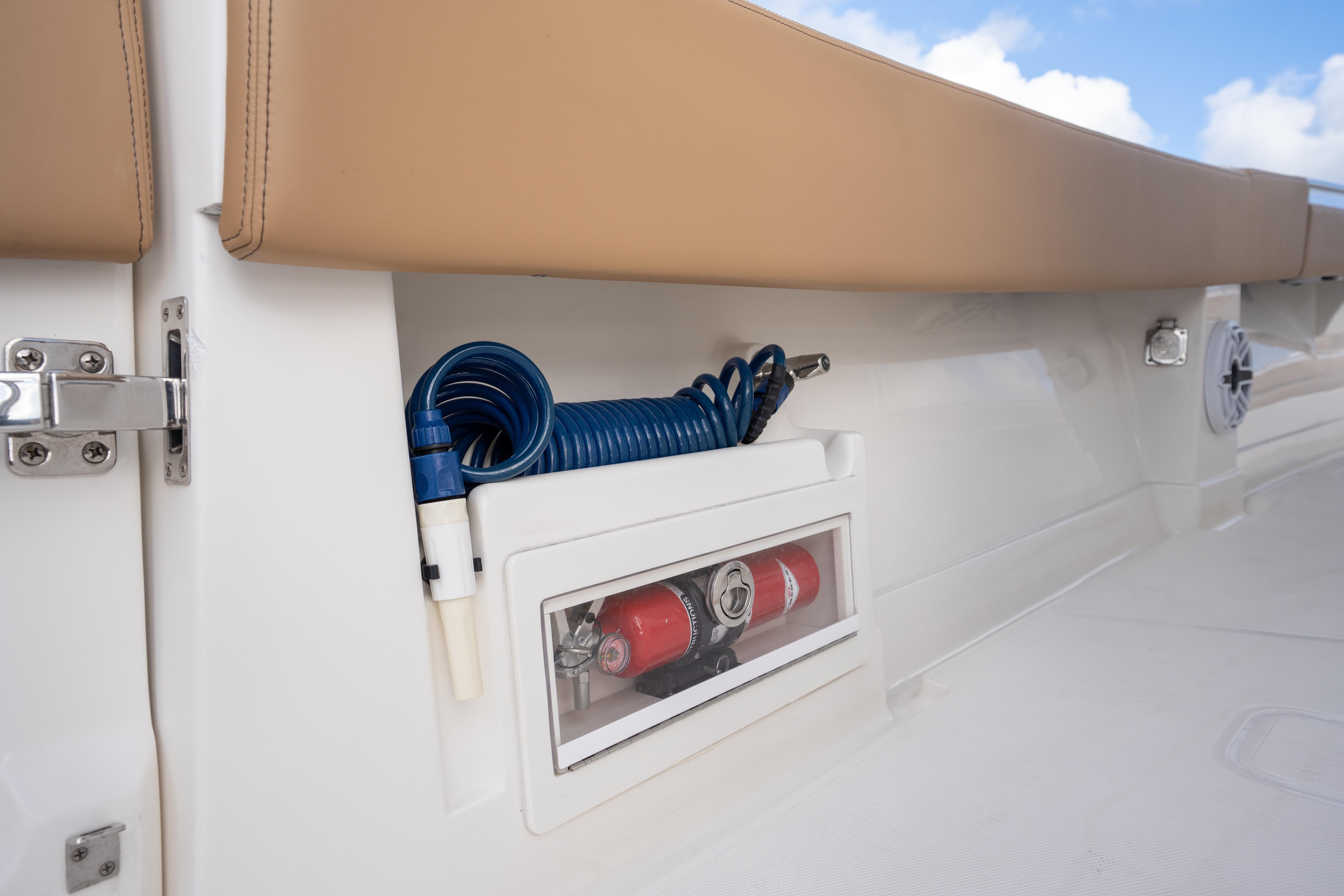 Storage compartment on 2026 Blackwater 41 Performance Fish boat with coiled hose and fire extinguisher.