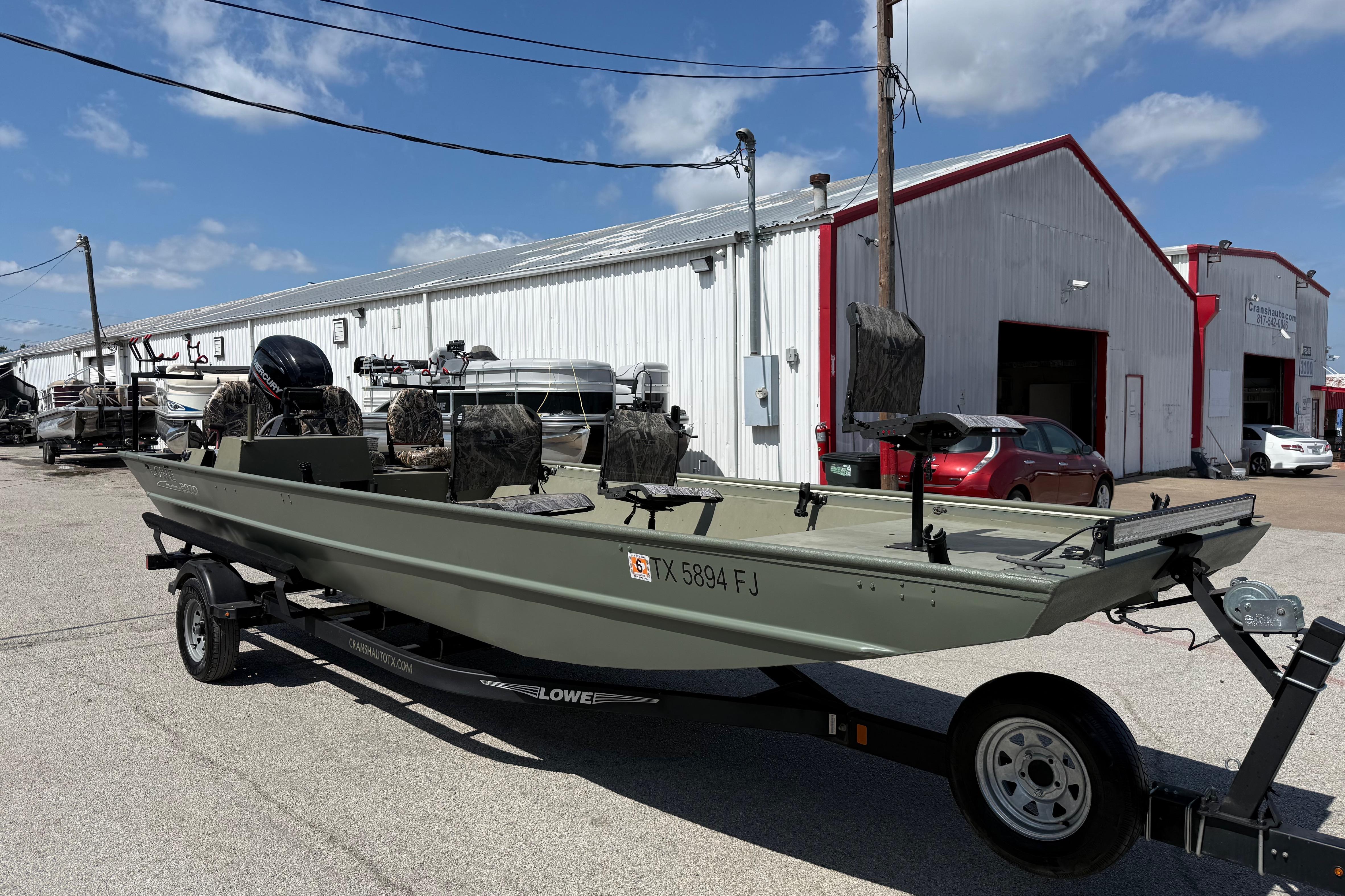 A 2020 Lowe Roughneck 2070 Big River boat on a trailer in front of a building.
