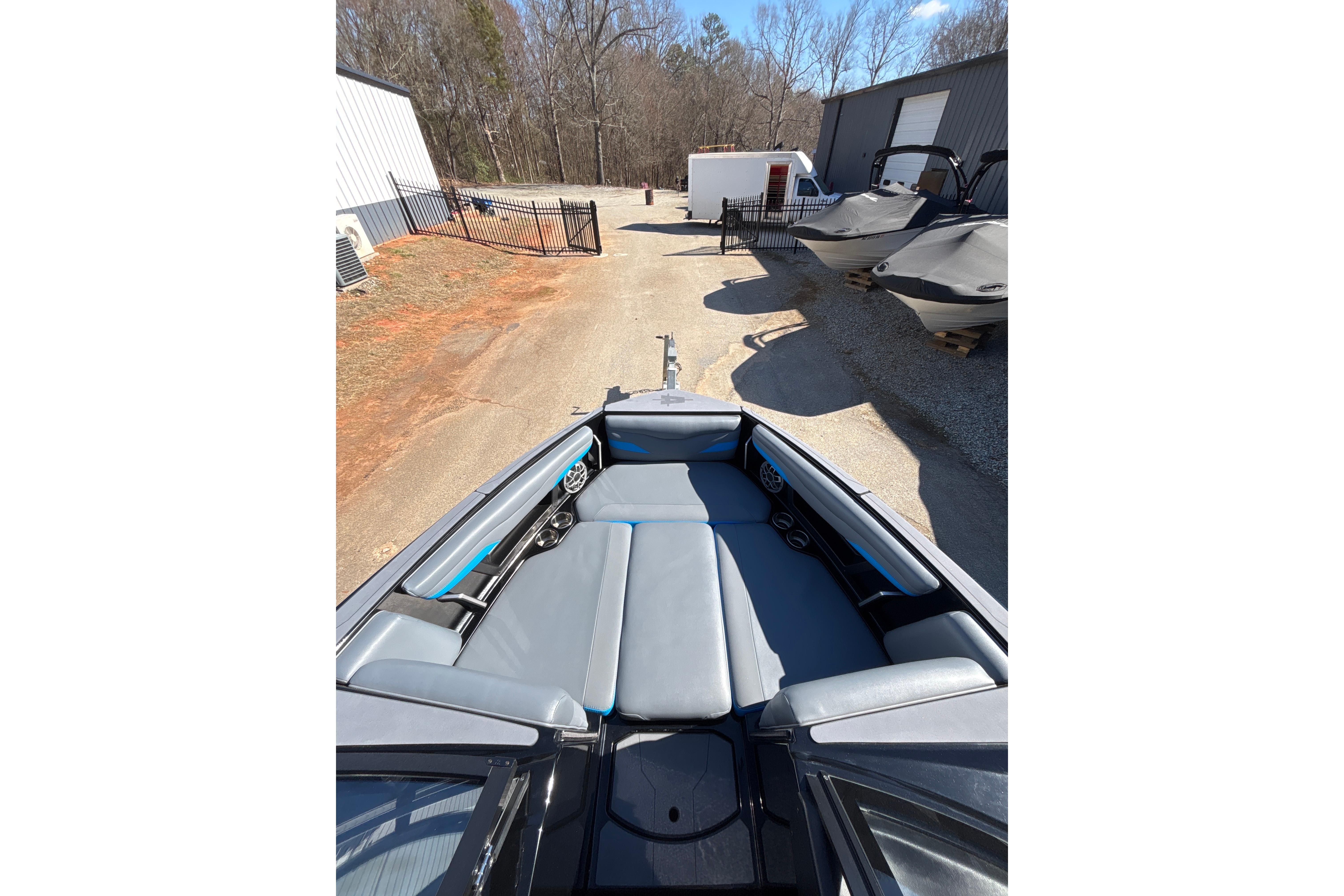 2023 Axis T220 boat interior with gray seating, parked outdoors near other boats.