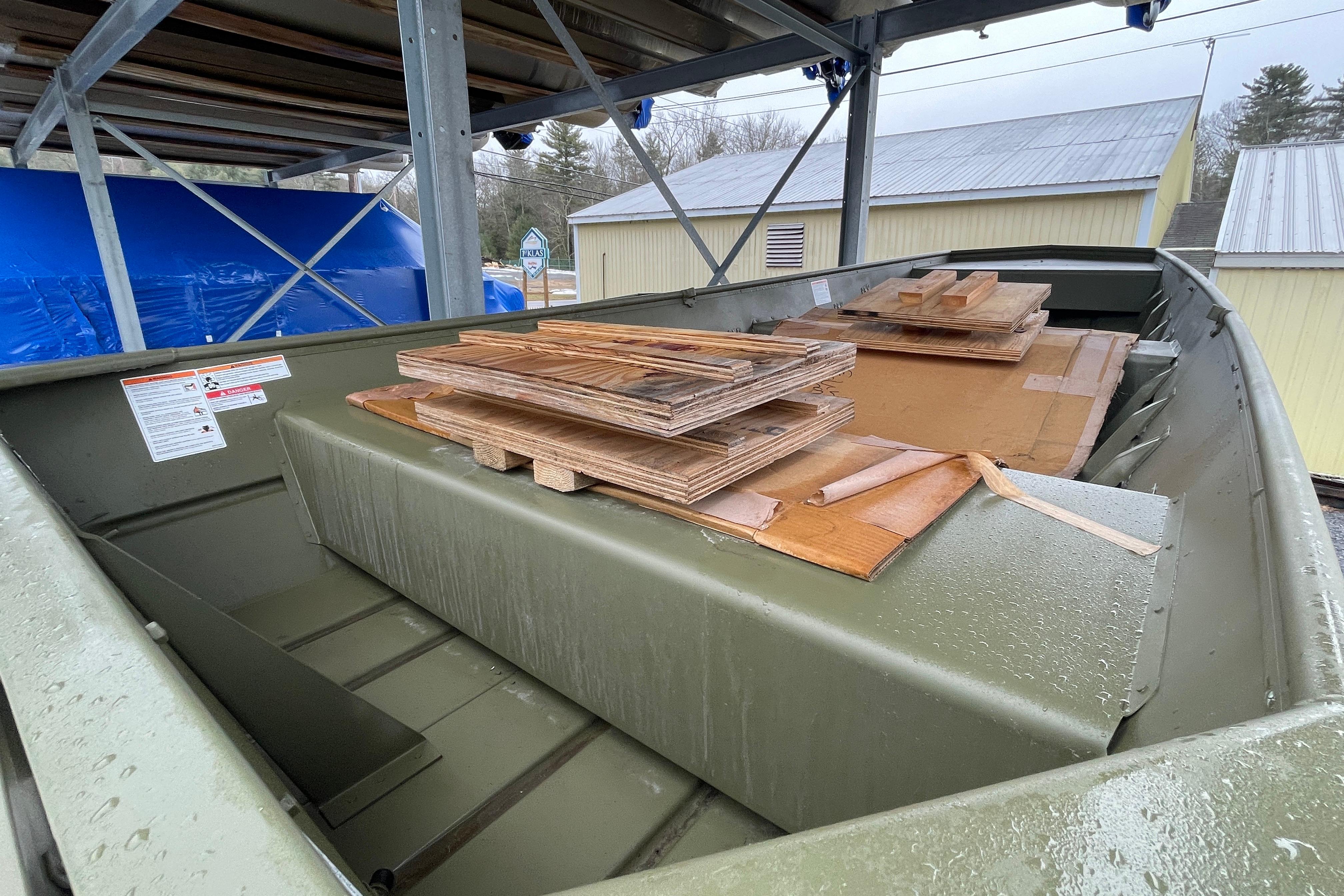2026 Lund 1648M boat with wooden pallets, stored under a metal structure.