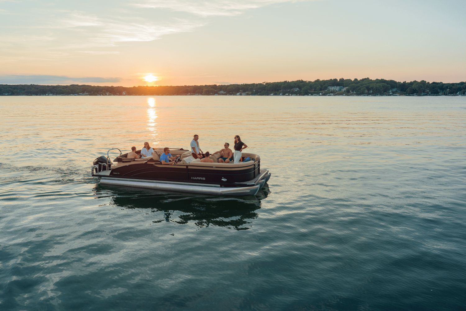 A group of people enjoying a boat ride on a calm lake at sunset.