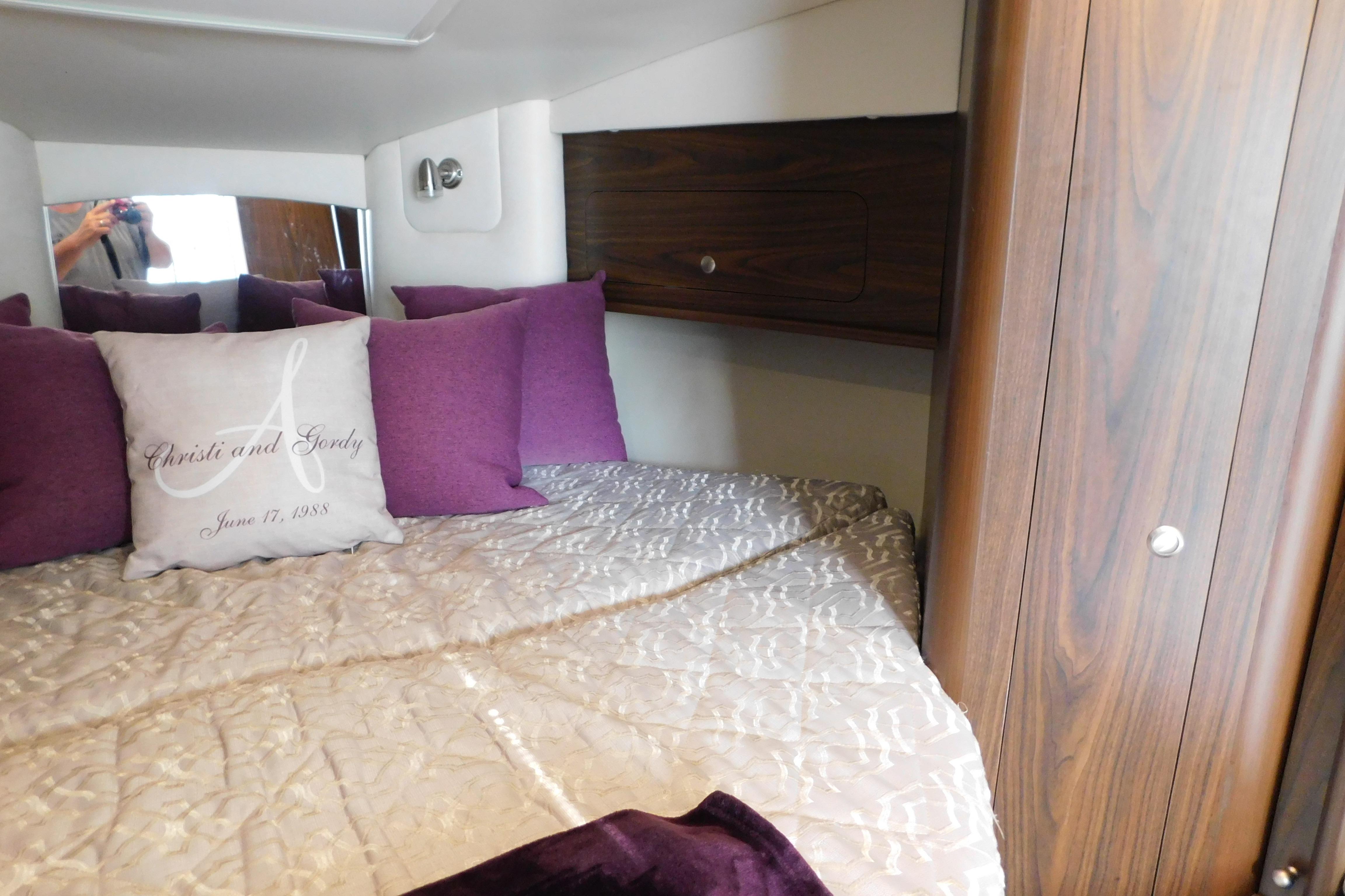 Cozy cabin interior of 2017 Rinker EX 320 with plush pillows and wood accents.