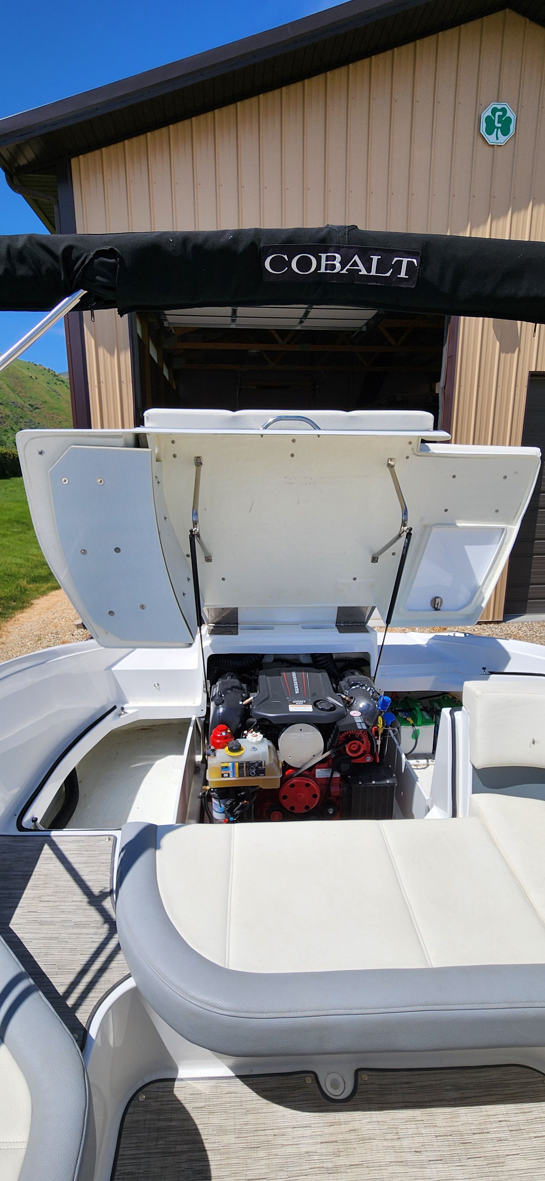 A Cobalt CS22 boat with an open engine compartment in front of a garage.